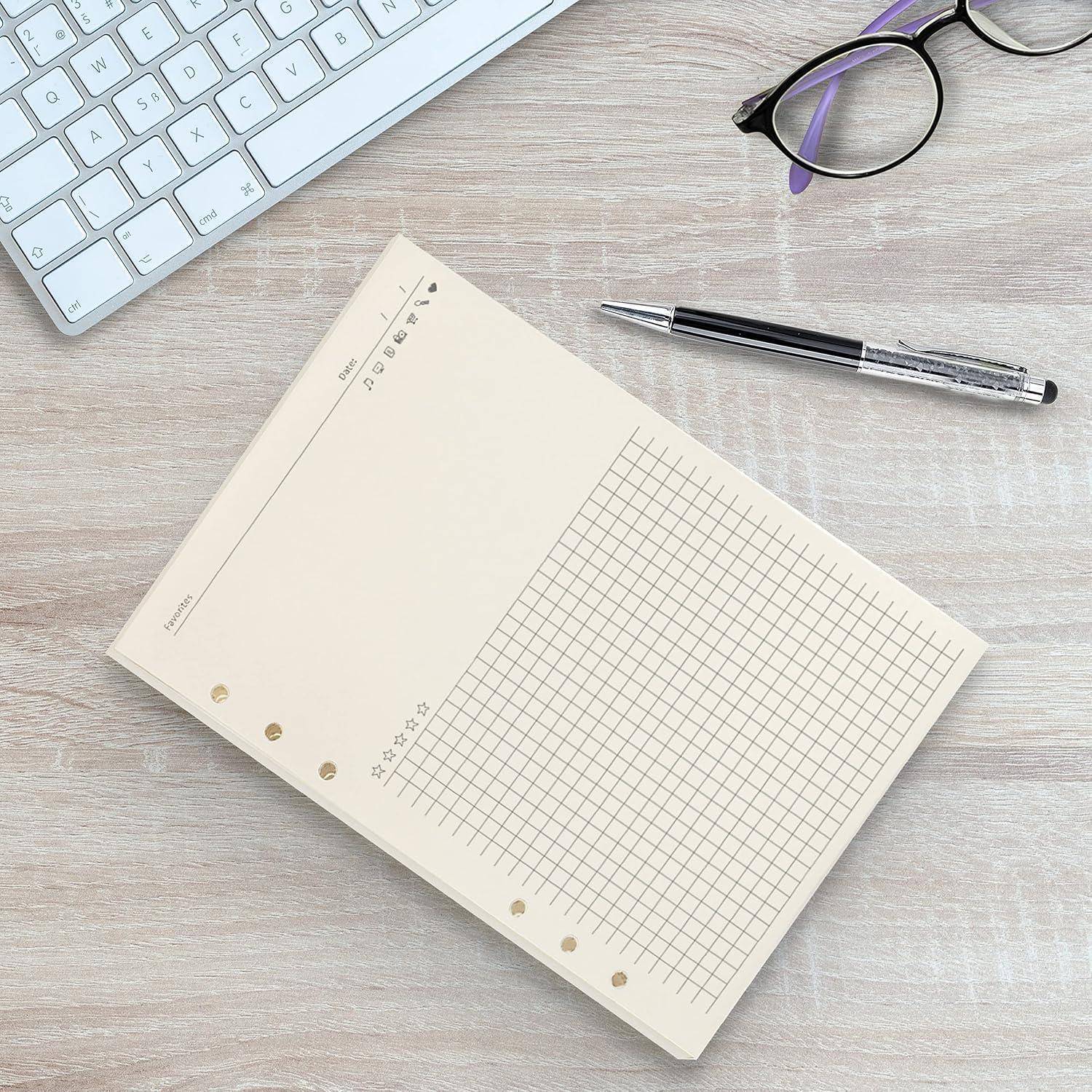 Schreibtischszene mit einem leeren Gitterblock, Stift, Brille und Tastatur auf einer hellen Holzoberfläche.