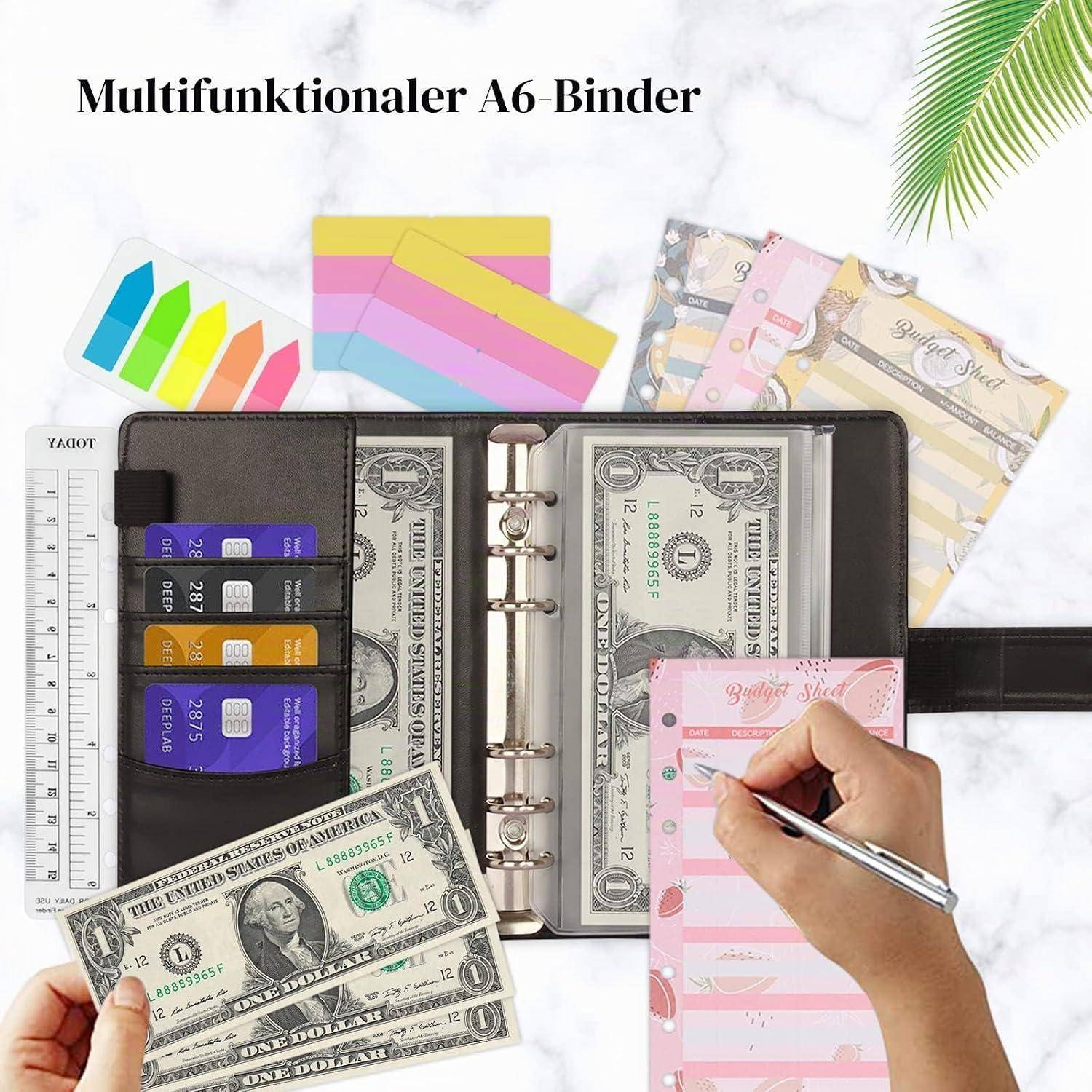 Ein multifunktionaler A6-Ringordner-Organizer, der offen liegt und U.S.-Dollar-Scheine, Karten, Reiter und eine Hand zeigt, die auf einem rosa Budgetblatt schreibt.