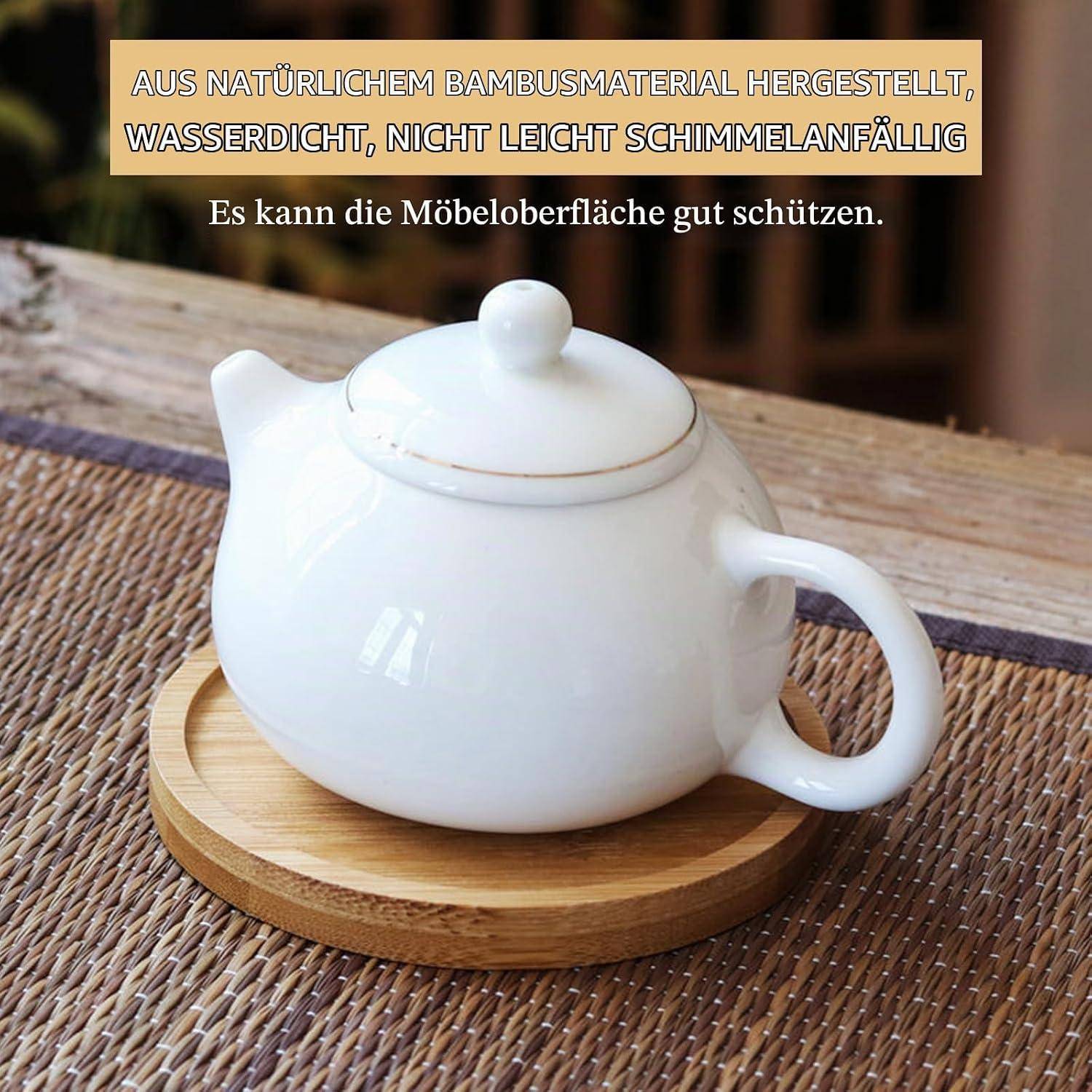 Weiße Teekanne auf einem runden Bambusuntersetzer auf einem geflochtenen Tisch, mit deutschem Text, der natürliches Bambousmaterial bewirbt, das wasserfest und schimmelresistent ist.