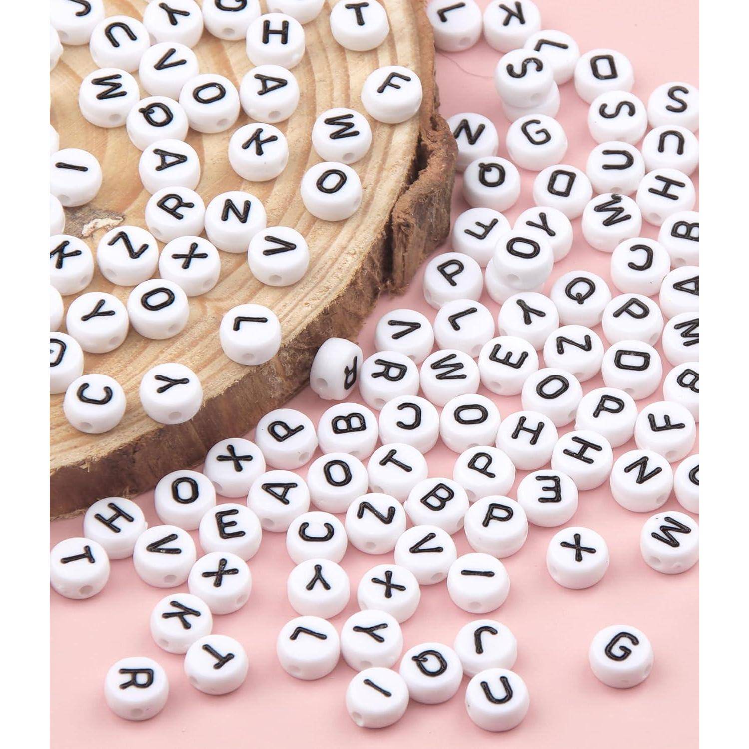Weiße Alphabet-Perlen, die auf rosa Hintergrund neben einer Holzscheibe verstreut sind, mit zufällig gemischten Buchstaben und einigen zusammengehäuften Perlen.