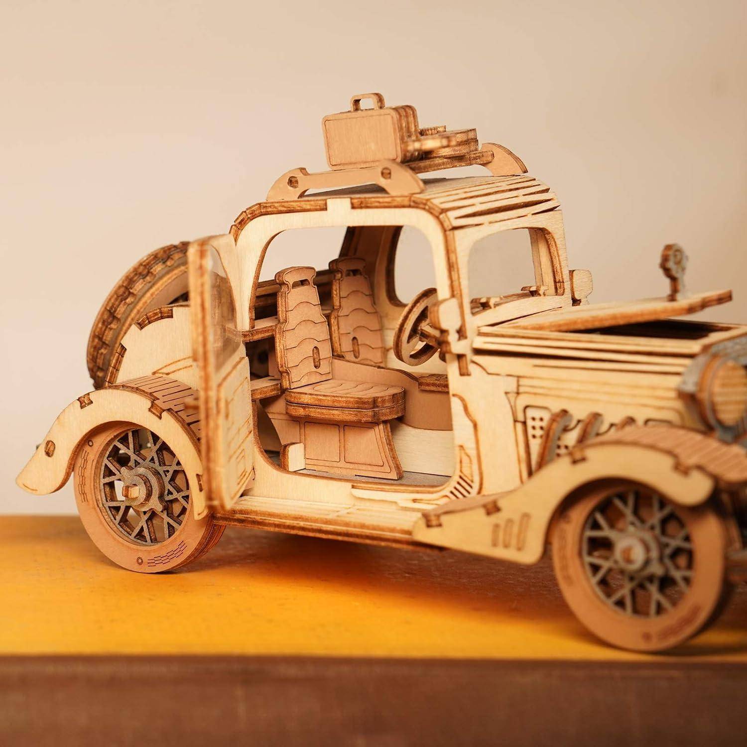 Holzmodell eines Vintage-Autos mit offener Tür, das detailliertes Innenraumdesign und Räder auf einer Tischplatte zeigt.