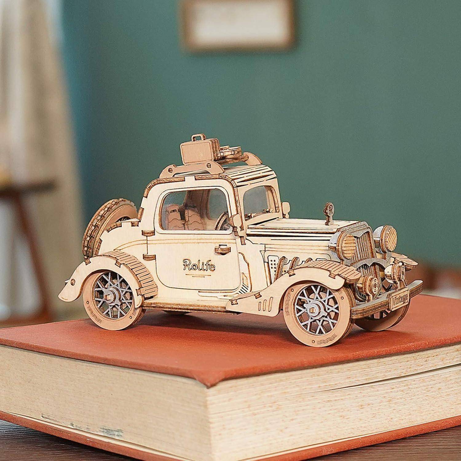 Holzmodell eines Vintage-Autos mit Gepäck auf einem Buch, präsentiert als dekoratives Tischobjekt.