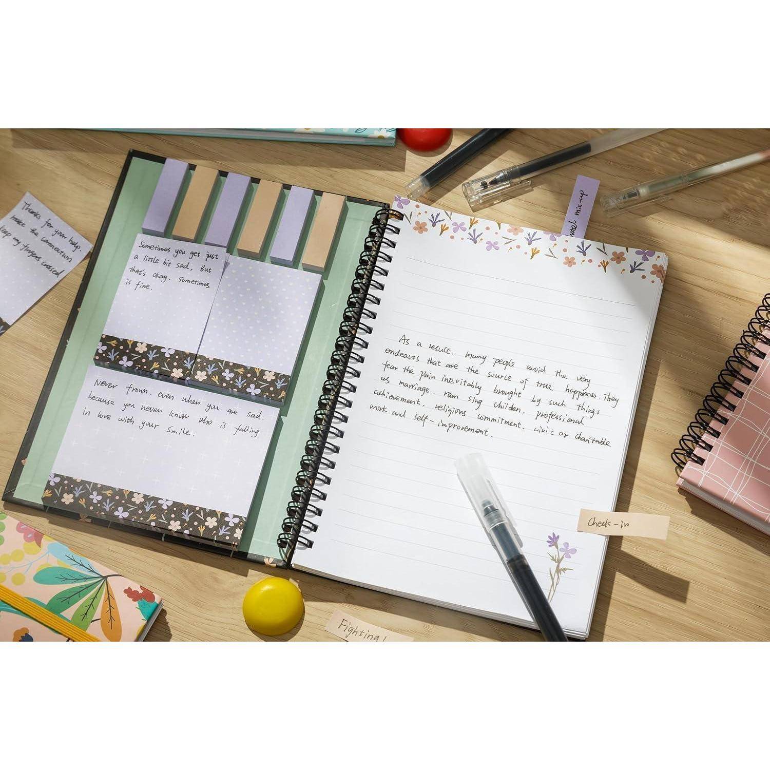 Offenes Spiralblöckchen mit handgeschriebenen Notizen und dekoriert gestalteten Plannerseiten auf einem Schreibtisch mit Stiften, Washi-Tape und Schreibwarenartikeln.