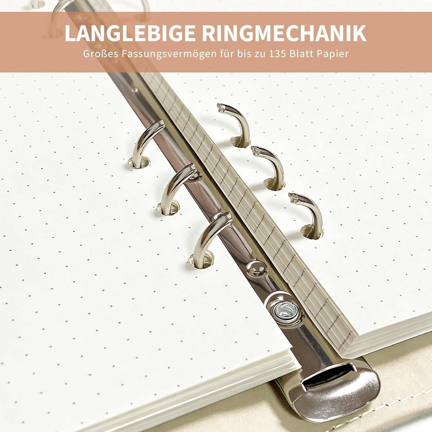 Nahaufnahme eines Ringbinder-Notizbuchs mit sechs Metallringen und punktierten Seiten, beschriftet auf Deutsch: „Langlebige Ringmechanik