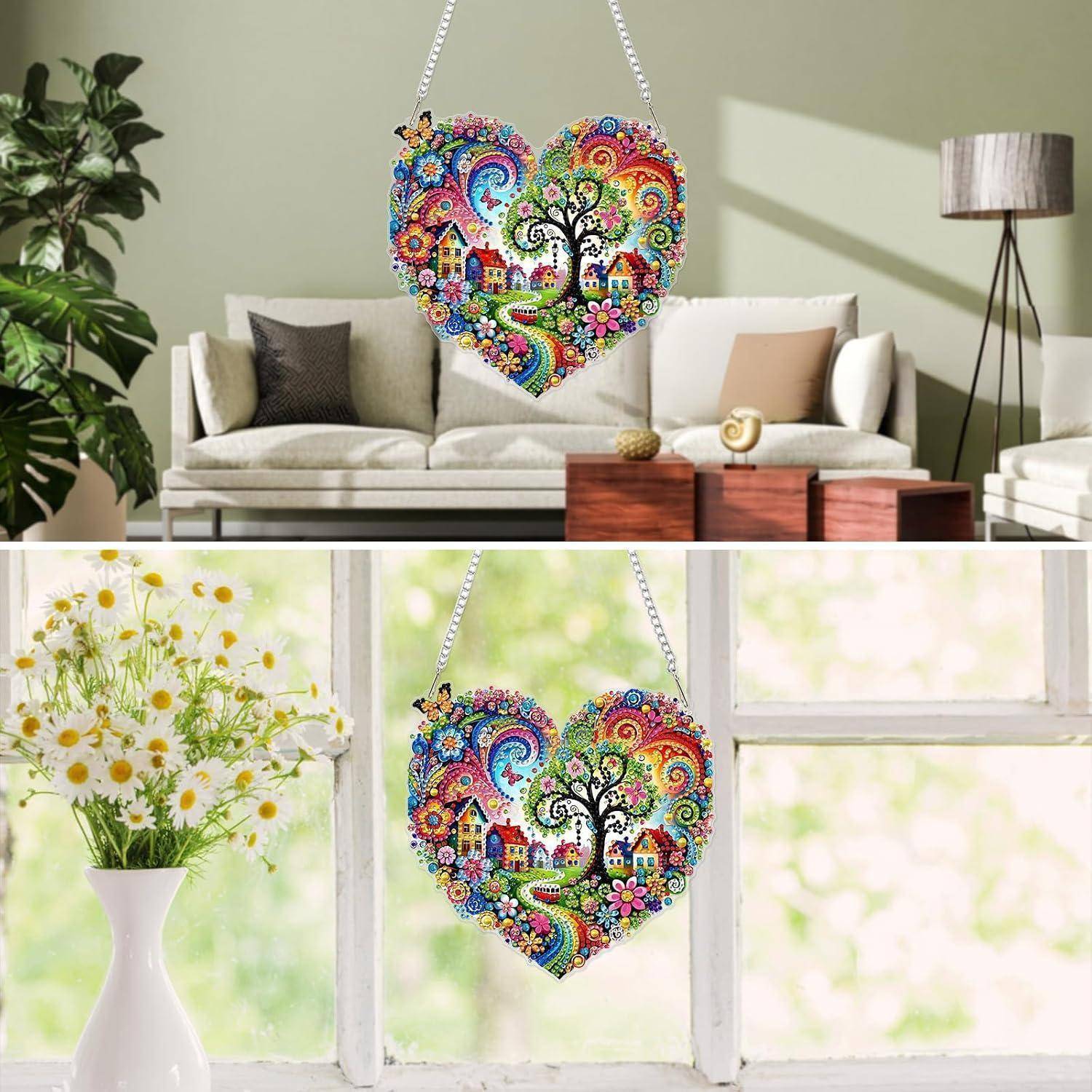 Herzförmige bunte Mosaikwandkunst eines Baumes und von Häusern, in einem Wohnzimmer ausgestellt und vor einem hellen Fenster hängend.