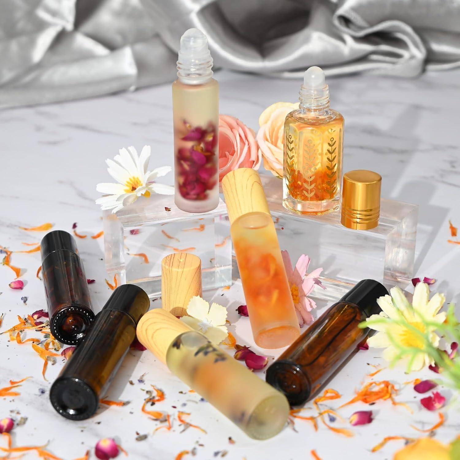 Assortierte dekorative Lipgloss-Röhrchen und kleine Serumflaschen mit Blüteneinschlüssen, arrangiert auf durchsichtigen Blöcken zwischen getrockneten Blütenblättern und Blüten.