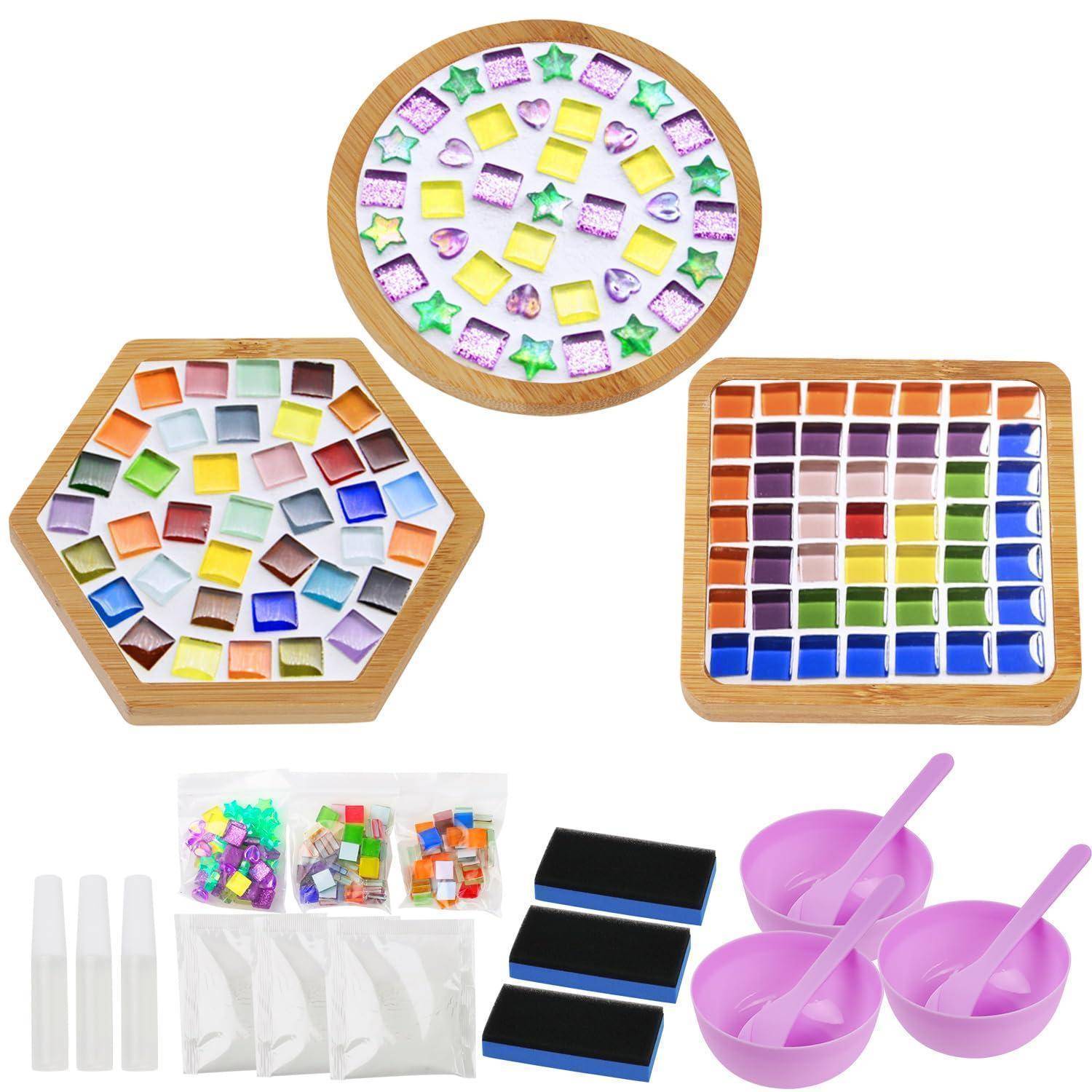 Mosaik-Kunstset mit drei Tabletts farbiger Glaskacheln, Leimtuben, Beuteln mit Teilen, schwarzen Unterlagen und violetten Rührschüsseln mit Spachteln.
