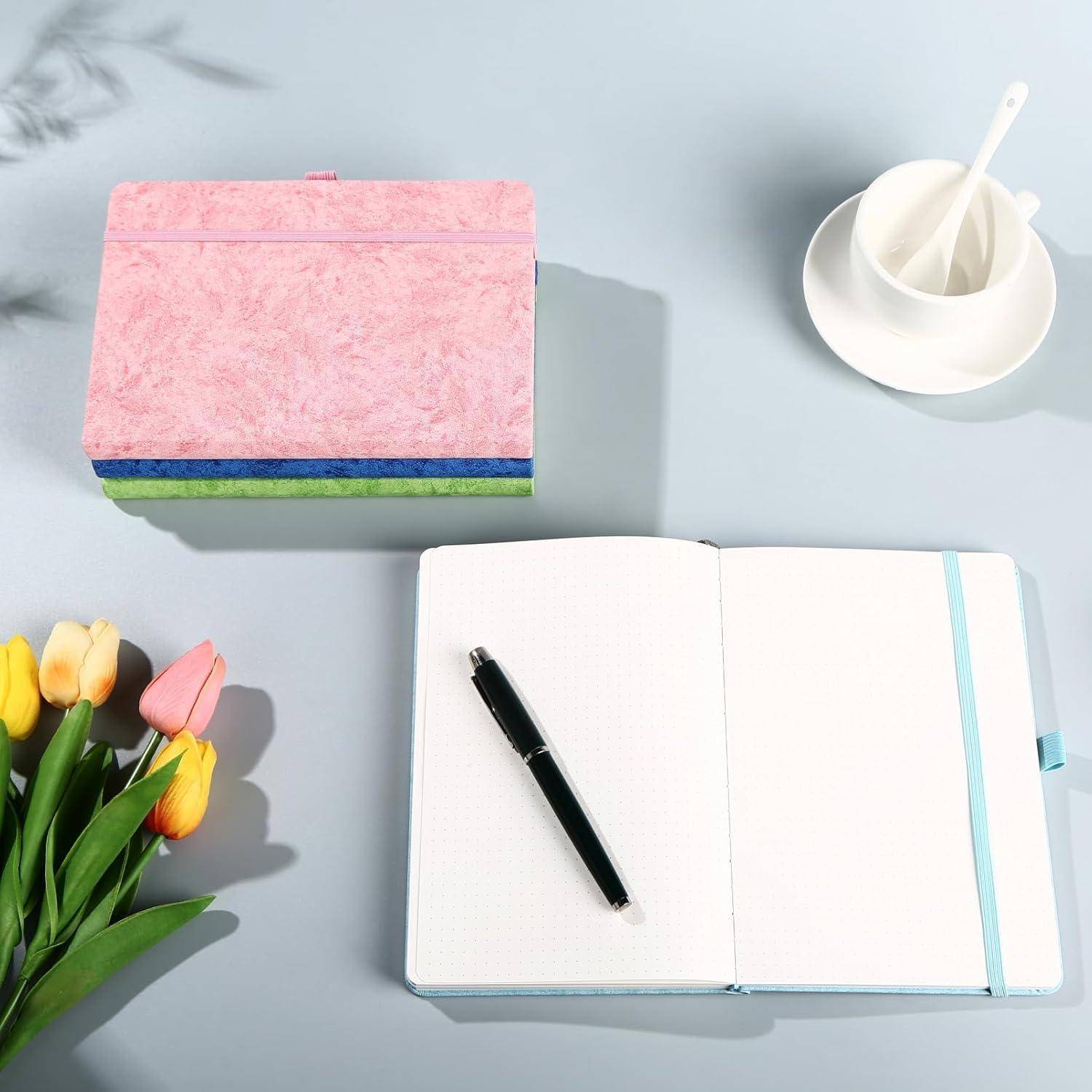 Draufsicht eines stillen Lebens mit einem rosa Notizbuch, geöffnetem Planer mit Stift, Tulpenstrauß und Tasse mit Löffel auf einem hellblauen Schreibtisch.