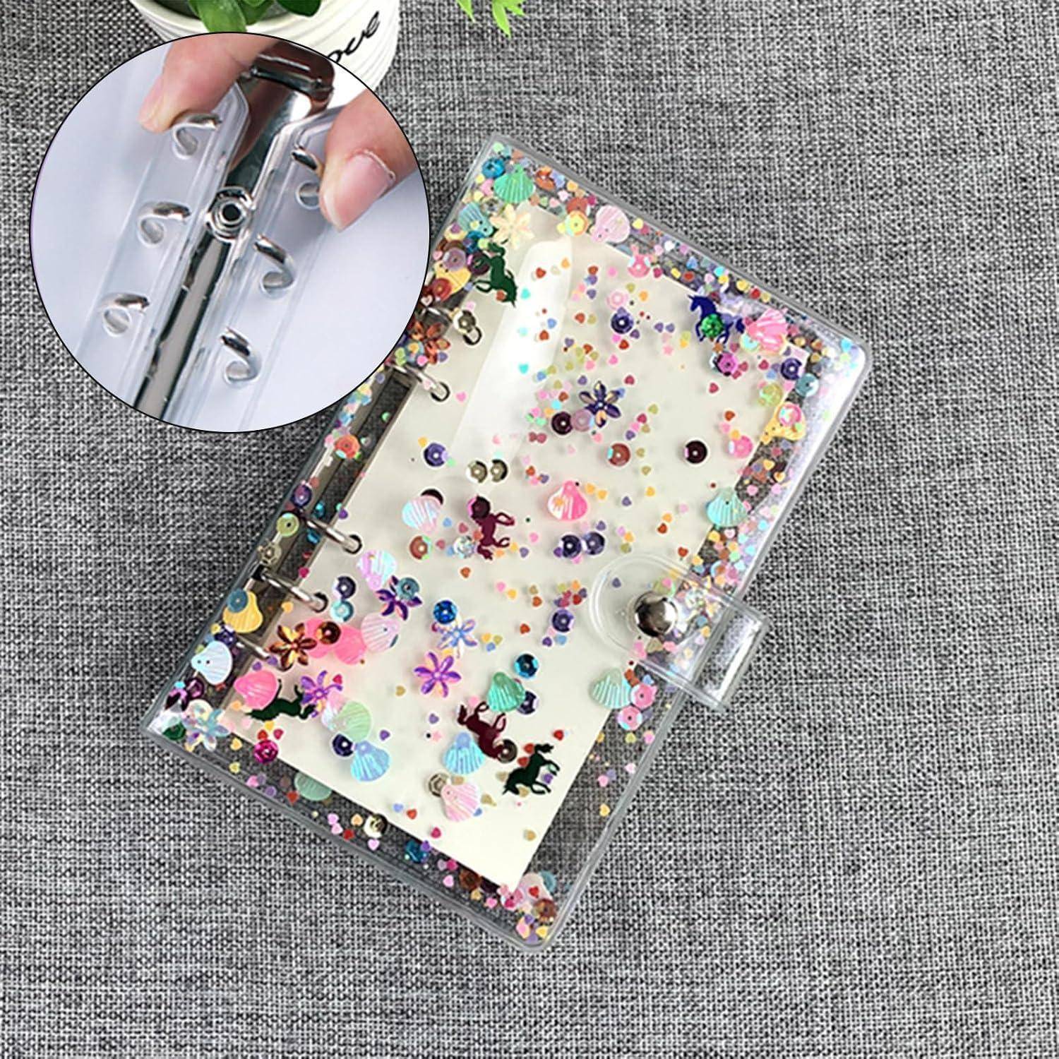 Transparente glittererfüllte Mappe mit Blumenconfetti auf grauem Stoff, geschlossen gezeigt mit einer Nahaufnahme des Ringmechanismus, der geöffnet wird.