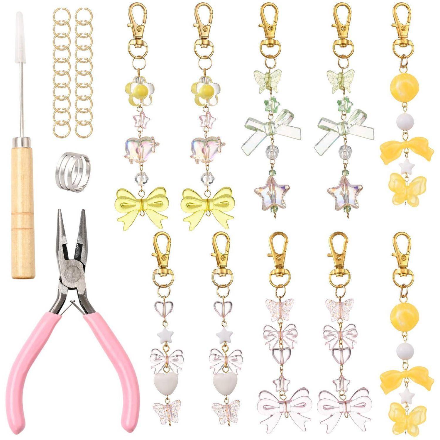 Handwerkzeuge und mehrere goldene Clip-Charms mit Schmetterlings- und Schleifendesigns, die in Reihen angeordnet sind, zusammen mit Zangen, einem Hakenwerkzeug und Sprungringen.