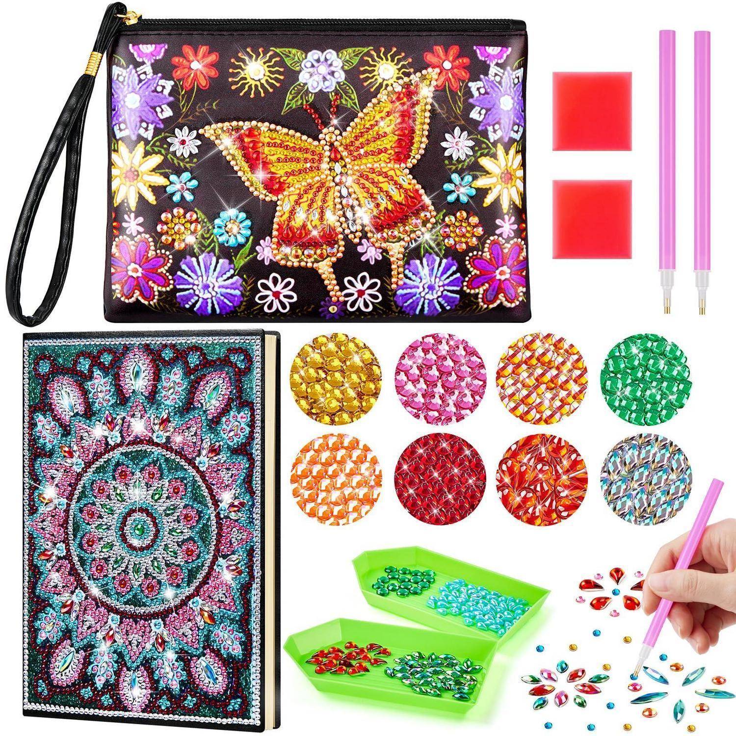 Diamantmalerei-Set mit verziertem Beutel und Notizbuch, zwei rosa Stift-Pens, Wachsblöcke, mehrere farbige Perlenpackungen, Tabletts und eine Hand, die Edelstein-Aufkleber in einem Muster anbringt.