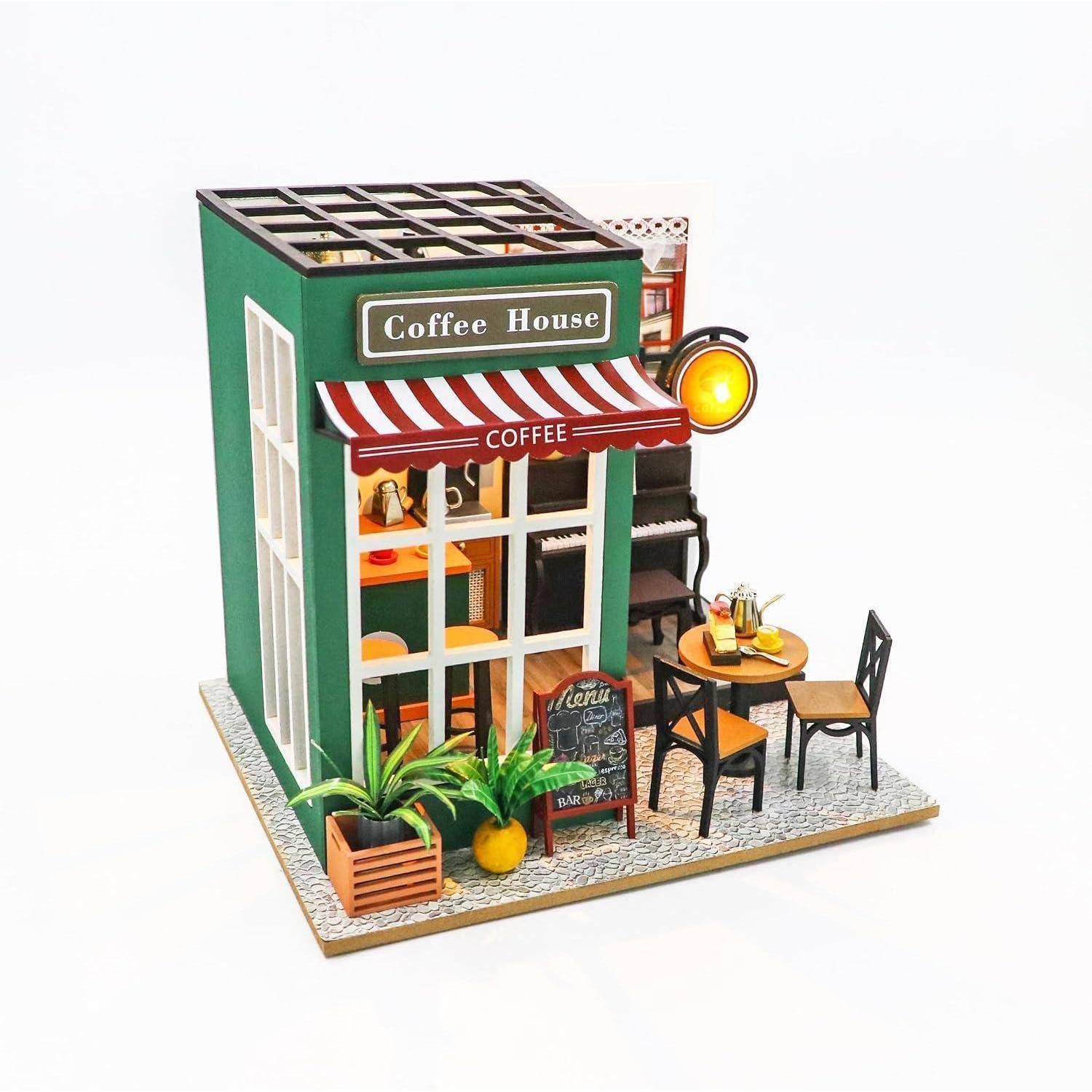 Miniatur-Kaffeehaus-Modell mit gestreifter Markise, Außentisch und Stühlen, Topfpflanzen und einem beleuchteten Schild mit der Aufschrift 