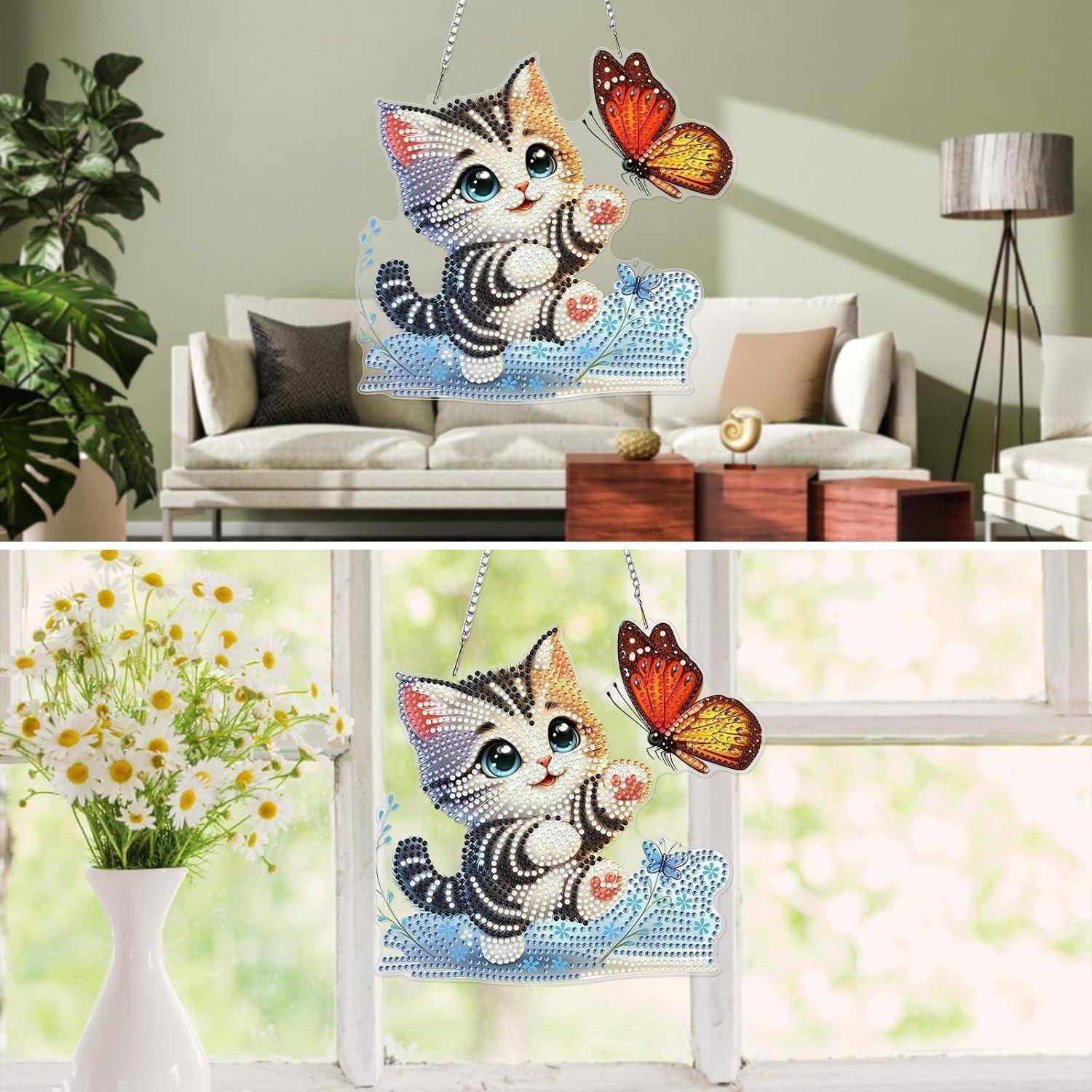 Glitzernde katzenfömige Hängdekoration mit einem Schmetterling, gezeigt in einem Wohnzimmer und an einem Fenster.