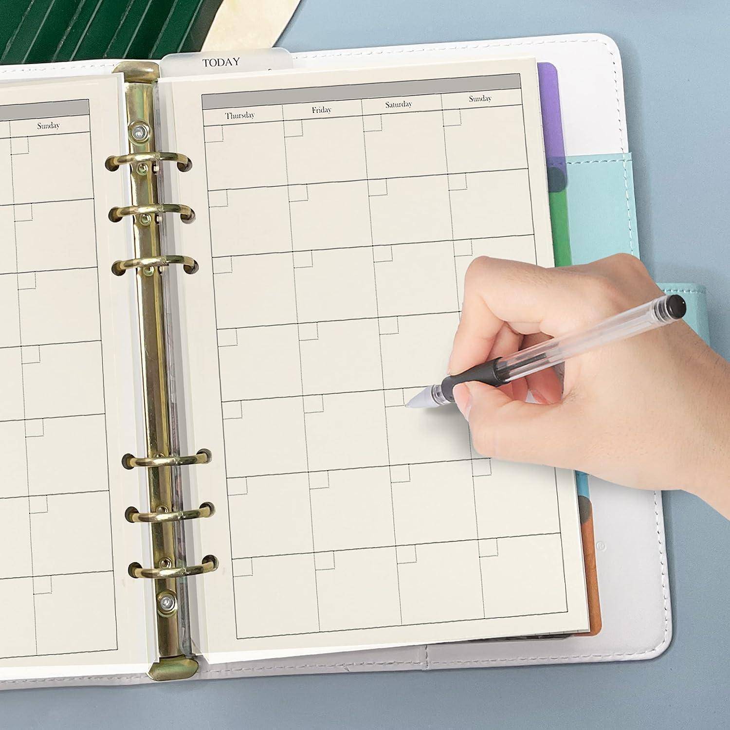 Handschrift in einem Ringbuch-Planungskalender, das Ausfüllen einer leeren monatlichen Terminseite mit einem Stift.