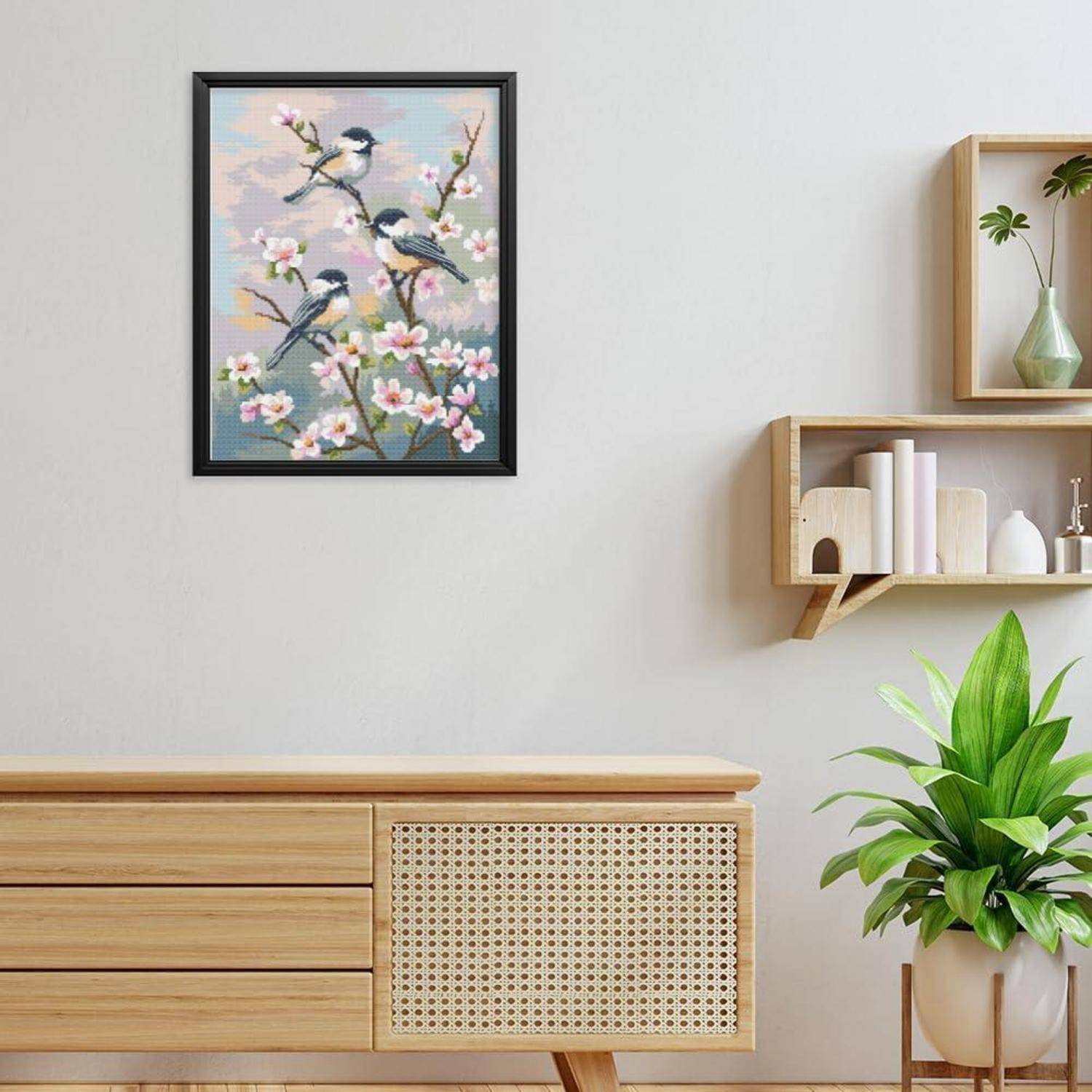 Minimalistisches Zimmer mit gerahmtem Vogel- und Blüten-Kunstwerk über einem Holz-Sideboard, Wandregalen mit Deko und einer Topfpflanze.