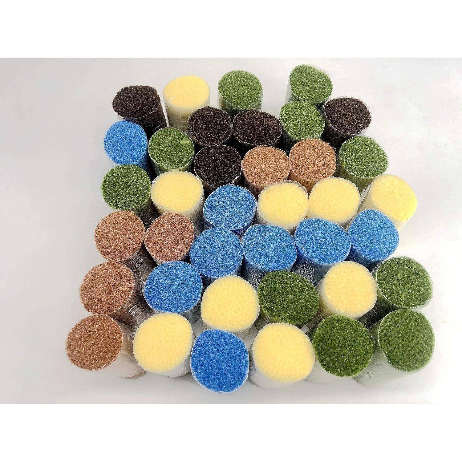 Stapel von kleinen runden Schleifpads in verschiedenen Farben – blau, gelb, grün, braun und schwarz – auf weißem Hintergrund angeordnet.