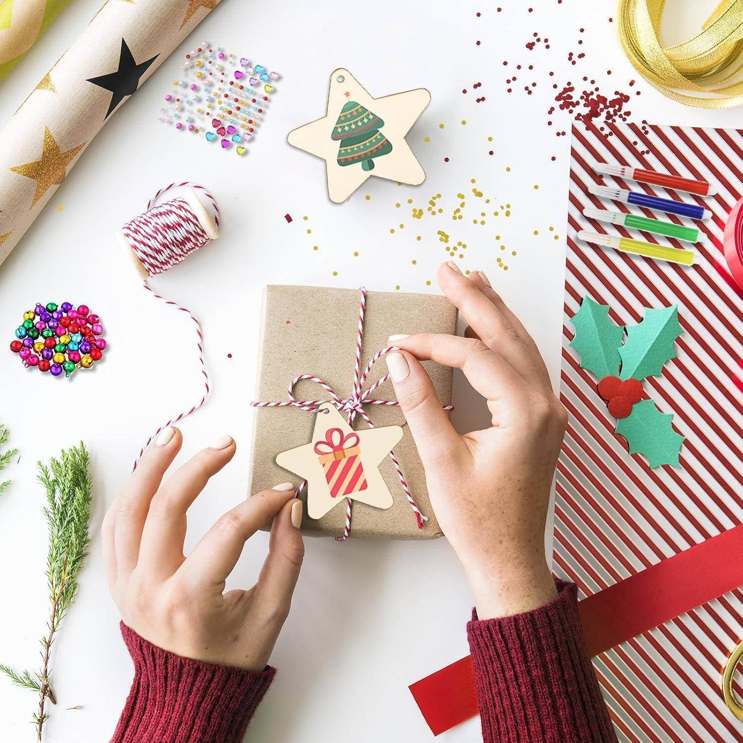 Hände wickeln ein mit Schnur gebundenes Geschenkkarton mit einer Sternenornament ein, umgeben von festlichen Verpackungsmaterialien, Bändern, Konfetti und Weihnachtsdekorationen.
