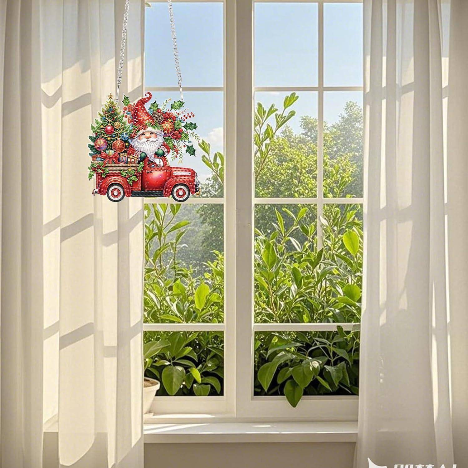 Weihnachtlicher Weihnachtsmann-im-roten-Lastwagen-Schmuck, der in einem sonnigen Fenster neben weißen Vorhängen hängt, mit grünem Laub draußen.