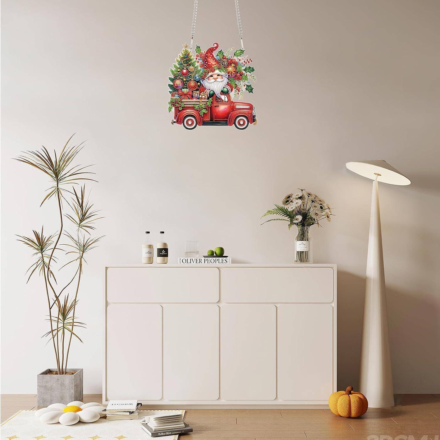 Ein Weihnachtsmann in einem roten Lastwagen Weihnachtswanddekoration hängt über einem minimalistischen Wohnzimmer mit weißem Schrank, Pflanzen, Lampe und Kürbissen.
