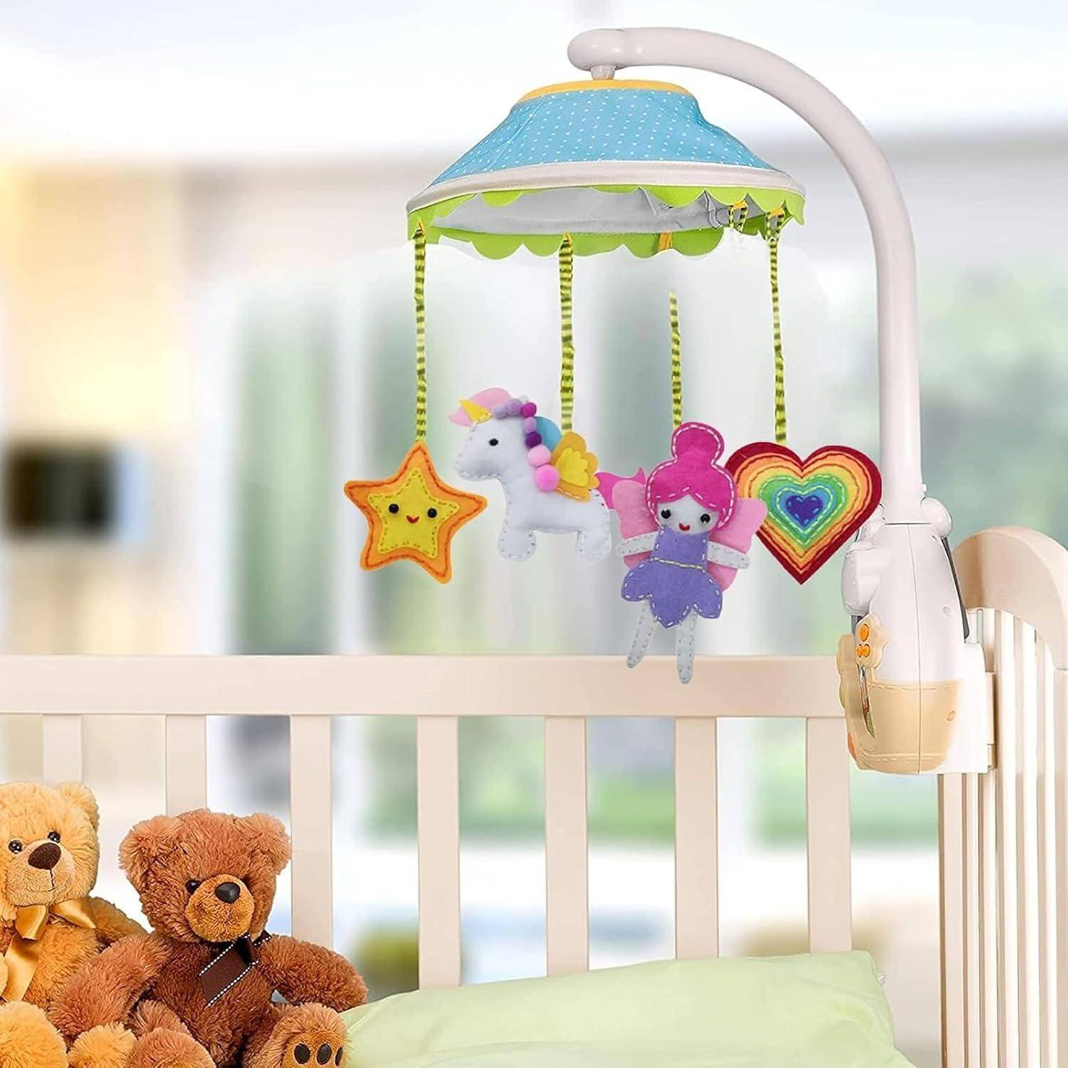 Mobile für Babybett mit hängenden Plüschsternen, Einhorn, Fee und Regenbogenherz über einem Babybett mit Teddybären und einem Kissen.