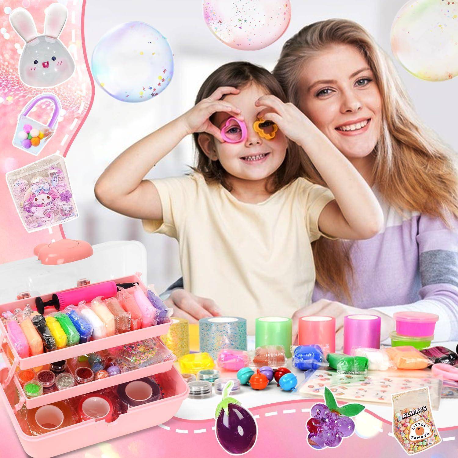 Lächelnde Frau und Kind posieren mit buntem Handwerksspielzeug, Aufklebern, Perlen und Schleim-Sets auf einem Tisch in einem verspielten Zimmer.
