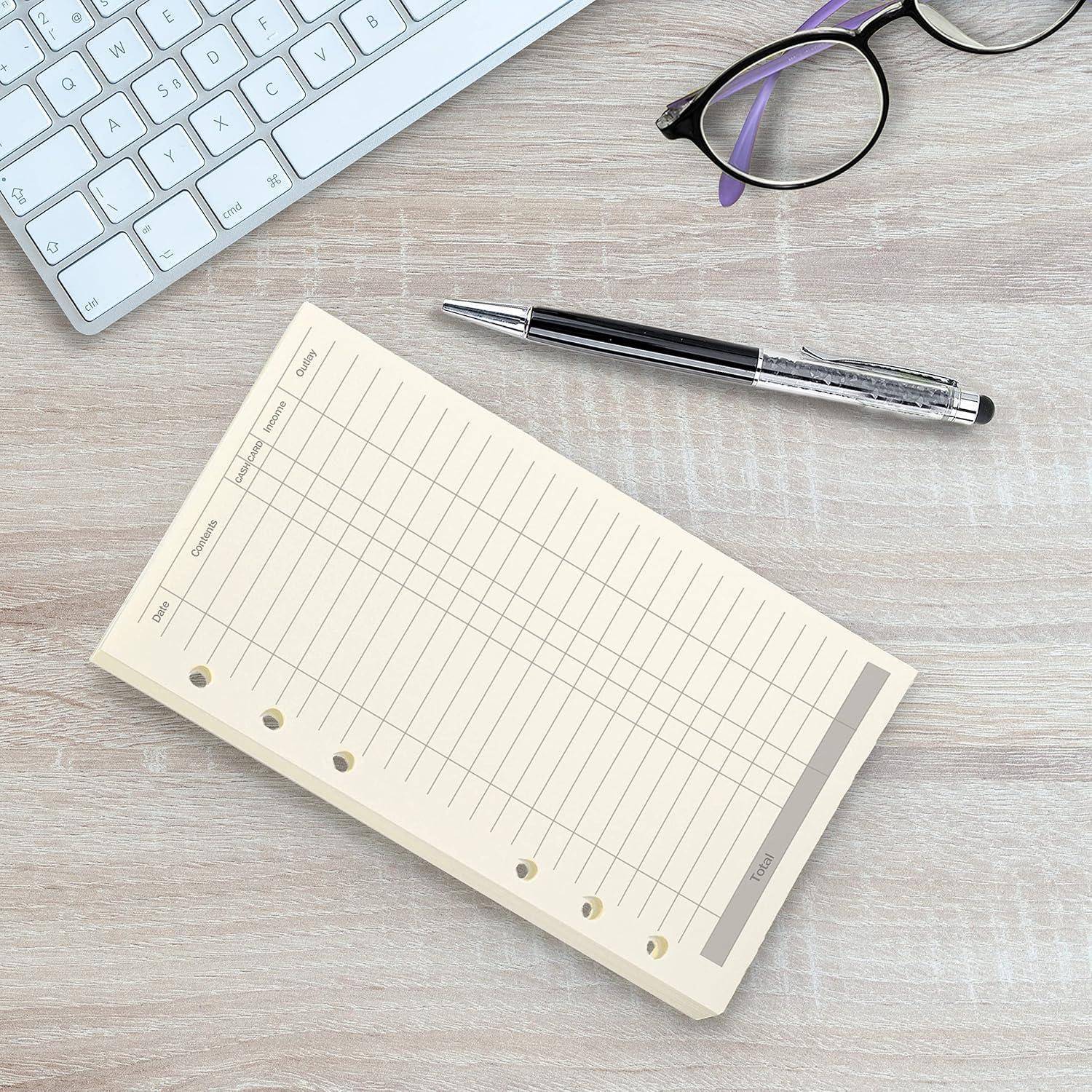 Leere Plannerseite mit Spalten und Zeilen neben einer Tastatur, einem Stift und einer Brille auf einem Schreibtisch.