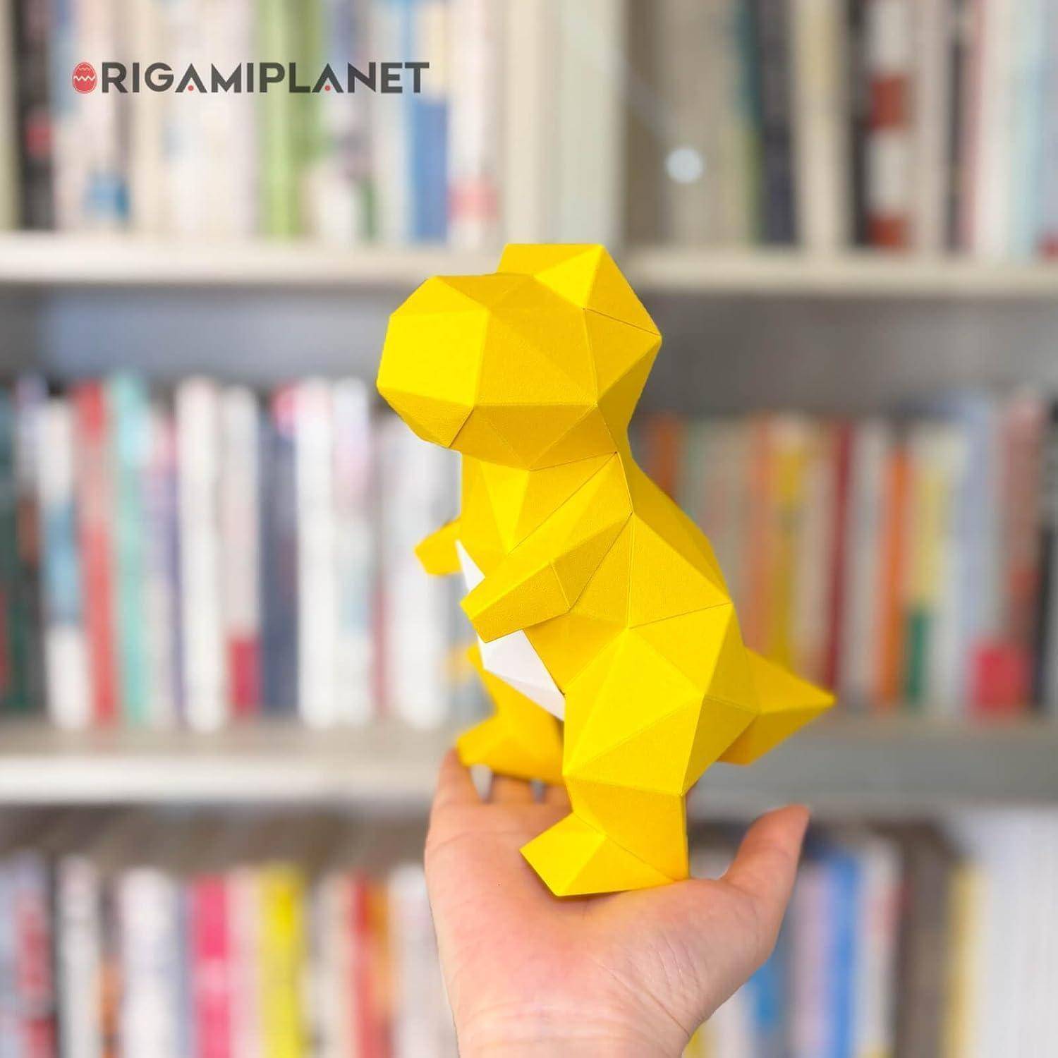 Eine Hand hält eine gelbe geometrische Dinosaurier-Figur vor einem unscharfen Bücherregal-Hintergrund.