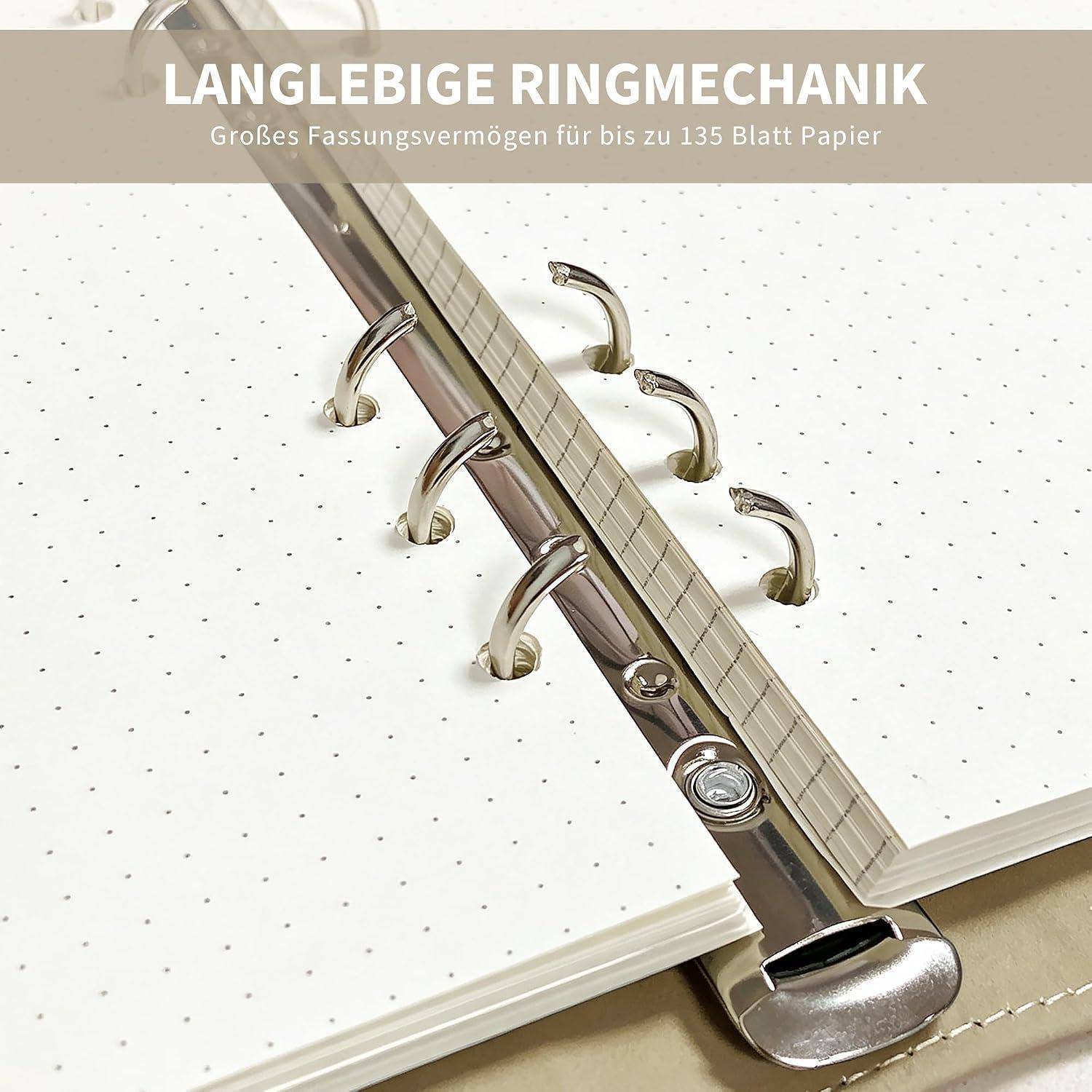 Nahaufnahme eines Ringbinders mit offenem gepunktetem Papier, das den Metallmechanismus und deutschen Text zeigt: 'LANGLEBIGE RINGMECHANIK' und 'Großes Fassungsvermögen für bis zu 135 Blatt Papier'.