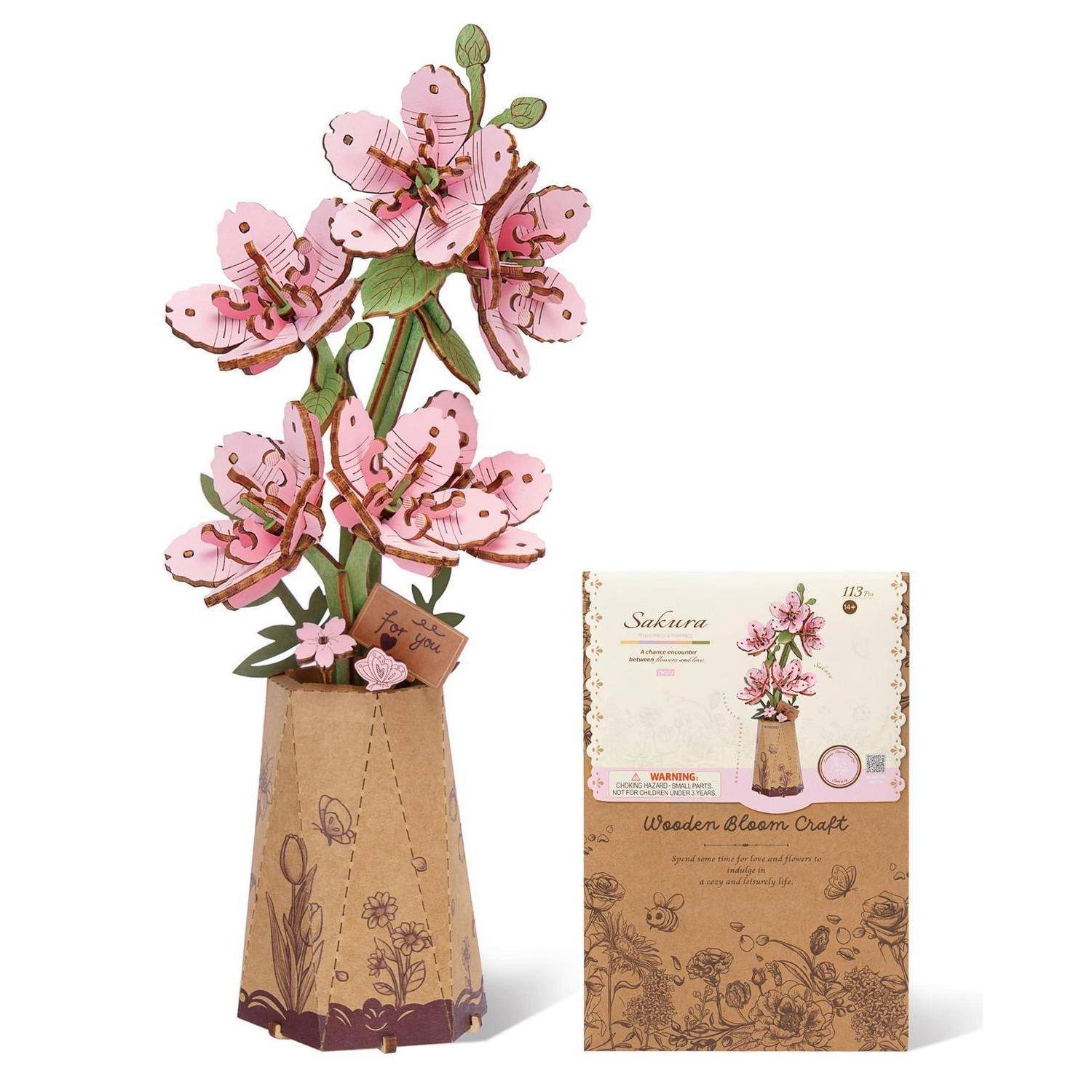 Rosa Sakura Holz-Blüten-Kunstwerk in einer dekorativen Vase, gezeigt neben seiner Produktbox-Verpackung.