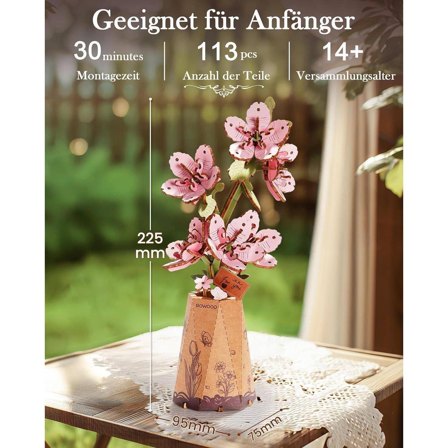 Bild eines rosa Blumenmodellbausatzes in einer Vase, auf Deutsch gekennzeichnet als anfängerfreundlich, 30 Minuten Zusammenbau, 113 Teile, ab 14 Jahren, 225 mm groß.