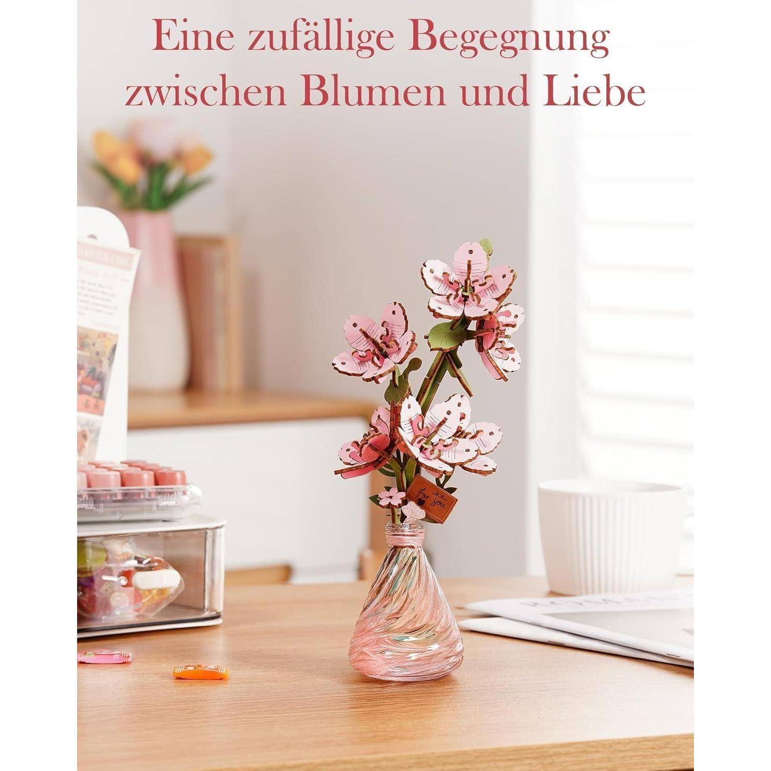Rosa Kirschblütenzweige in einer kleinen Vase auf einem Schreibtisch, mit deutschem Text darüber, der lautet „Eine zufällige Begegnung zwischen Blumen und Liebe