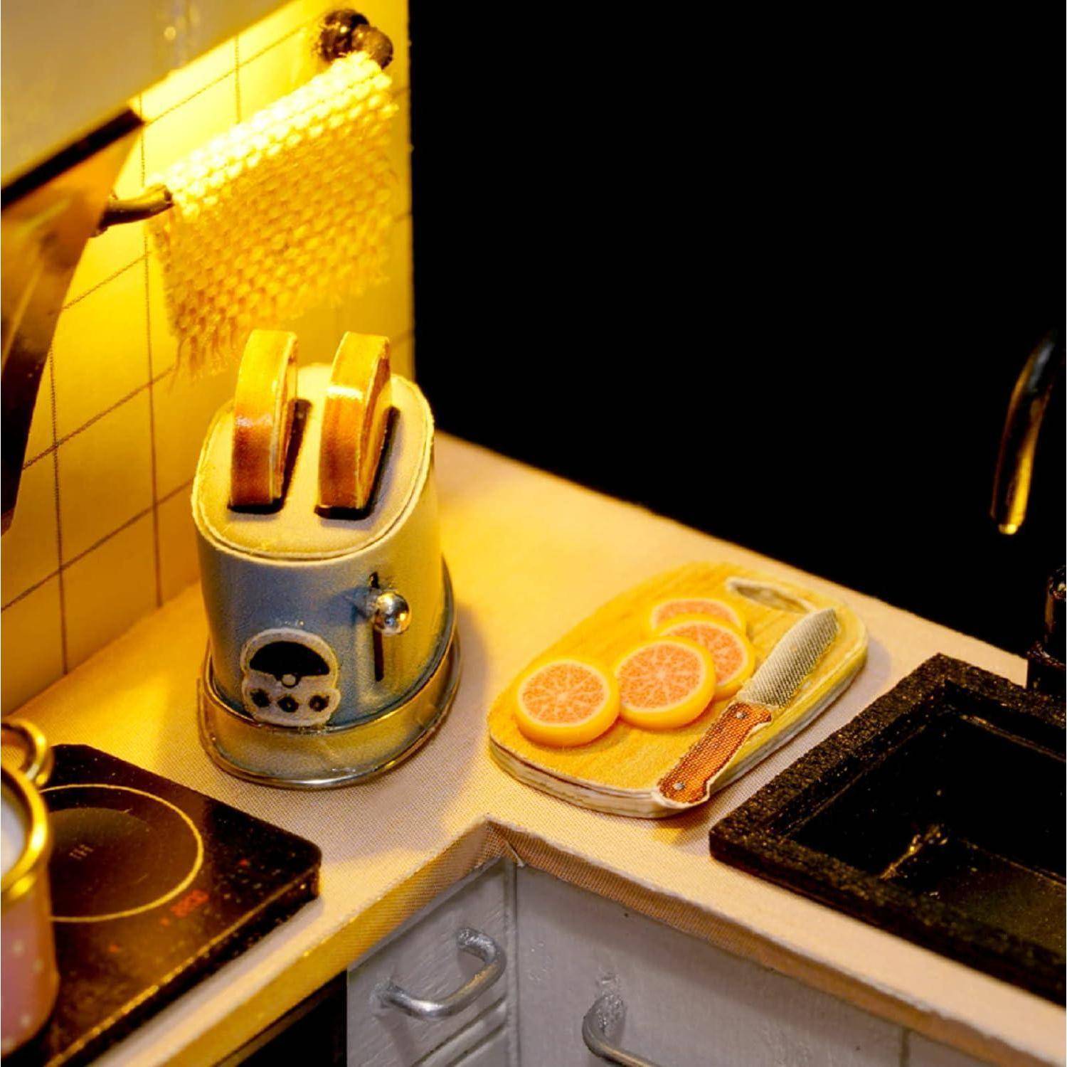Miniatur-Küchenszene mit einem Zwei-Schlitz-Toaster, geschnittenen Zitrusfrüchten auf einem Tablett und einem Spülbecken neben einem Kochfeld unter warmem Licht.