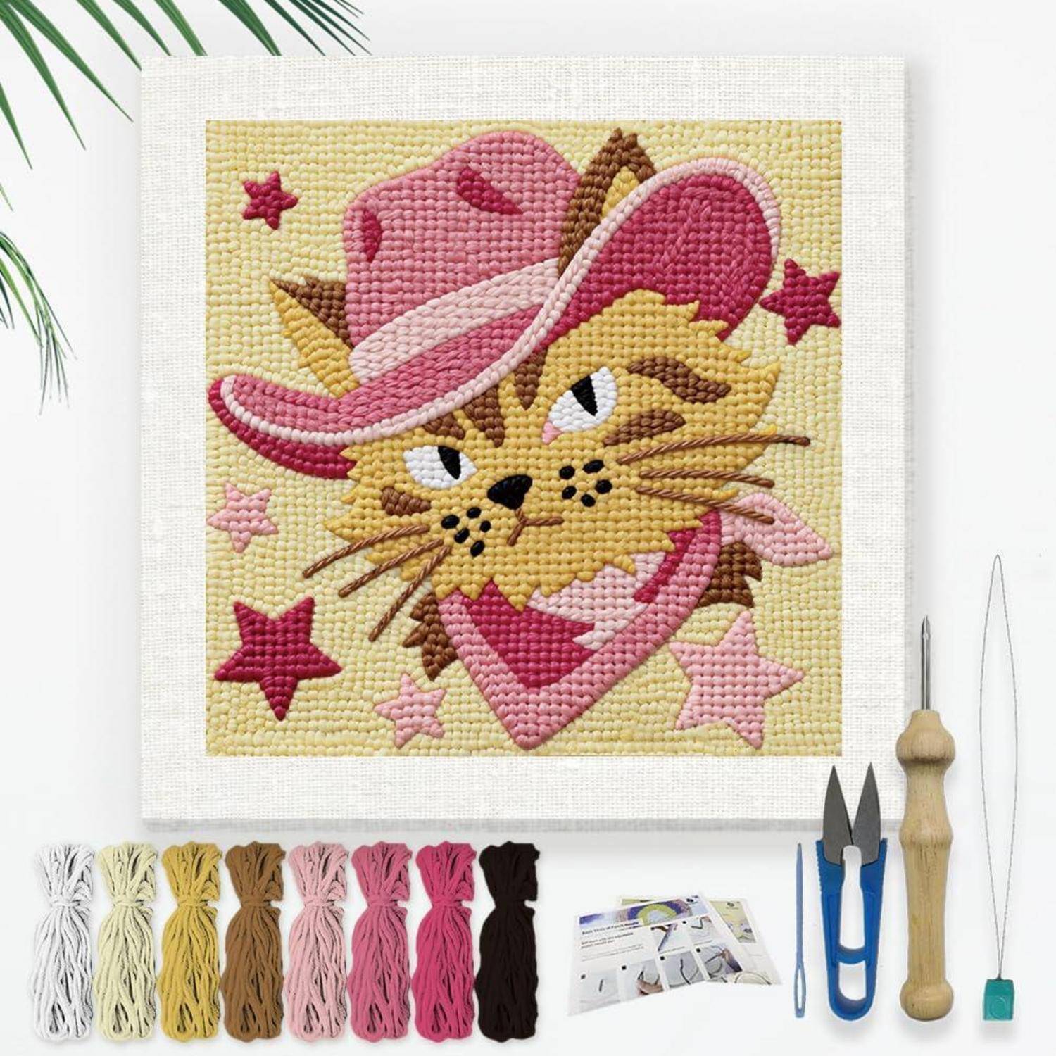 Stickpackung mit einer Katze in einem rosa Cowboyhut und Herz-Halstuch, mit Garnfarben, Werkzeugen und Anleitung unten angeordnet.