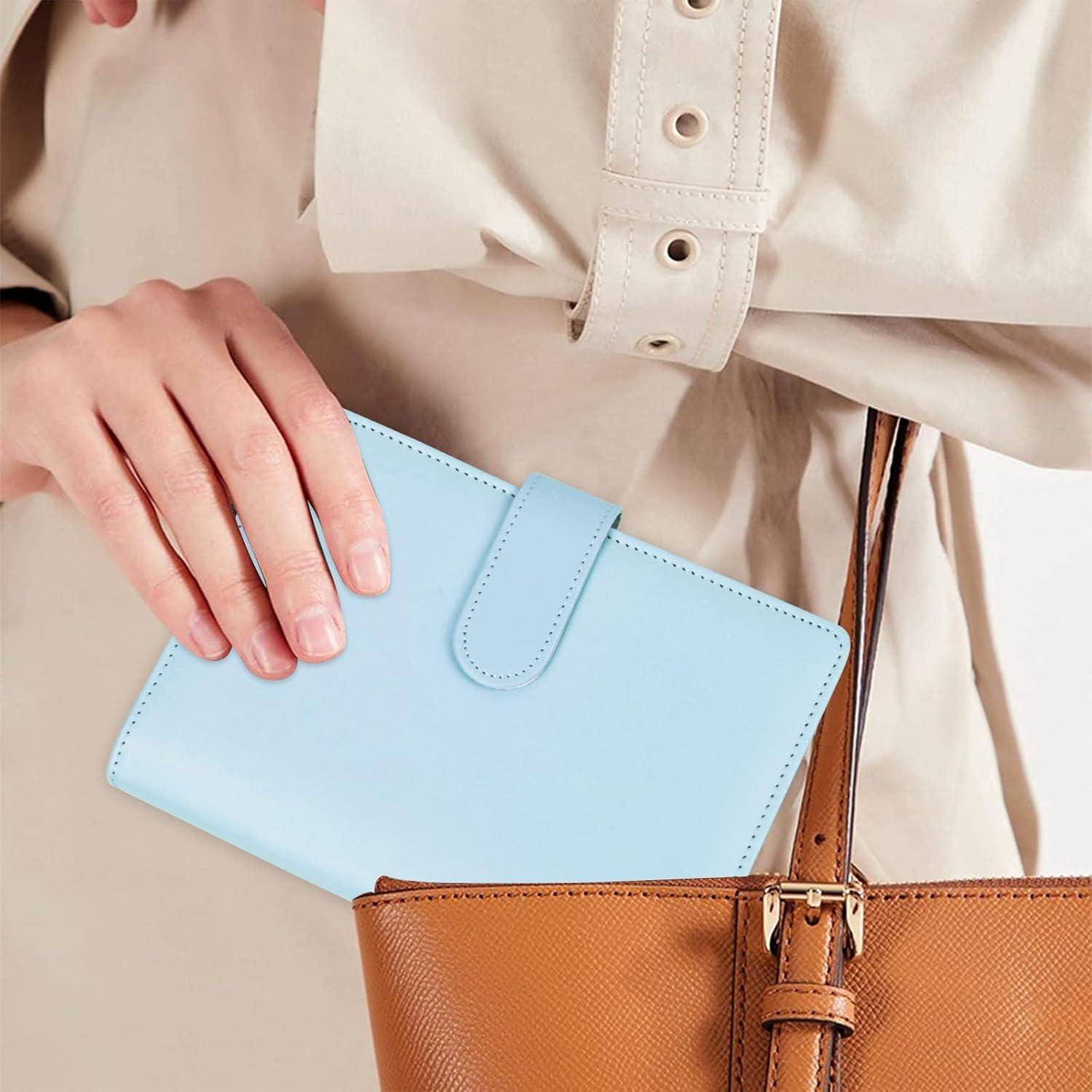 Person, die eine hellblaue Geldbörse über einer braunen Ledertasche hält, zeigt zwei aufeinander abgestimmte Accessoires in einer modischen Nahaufnahme.
