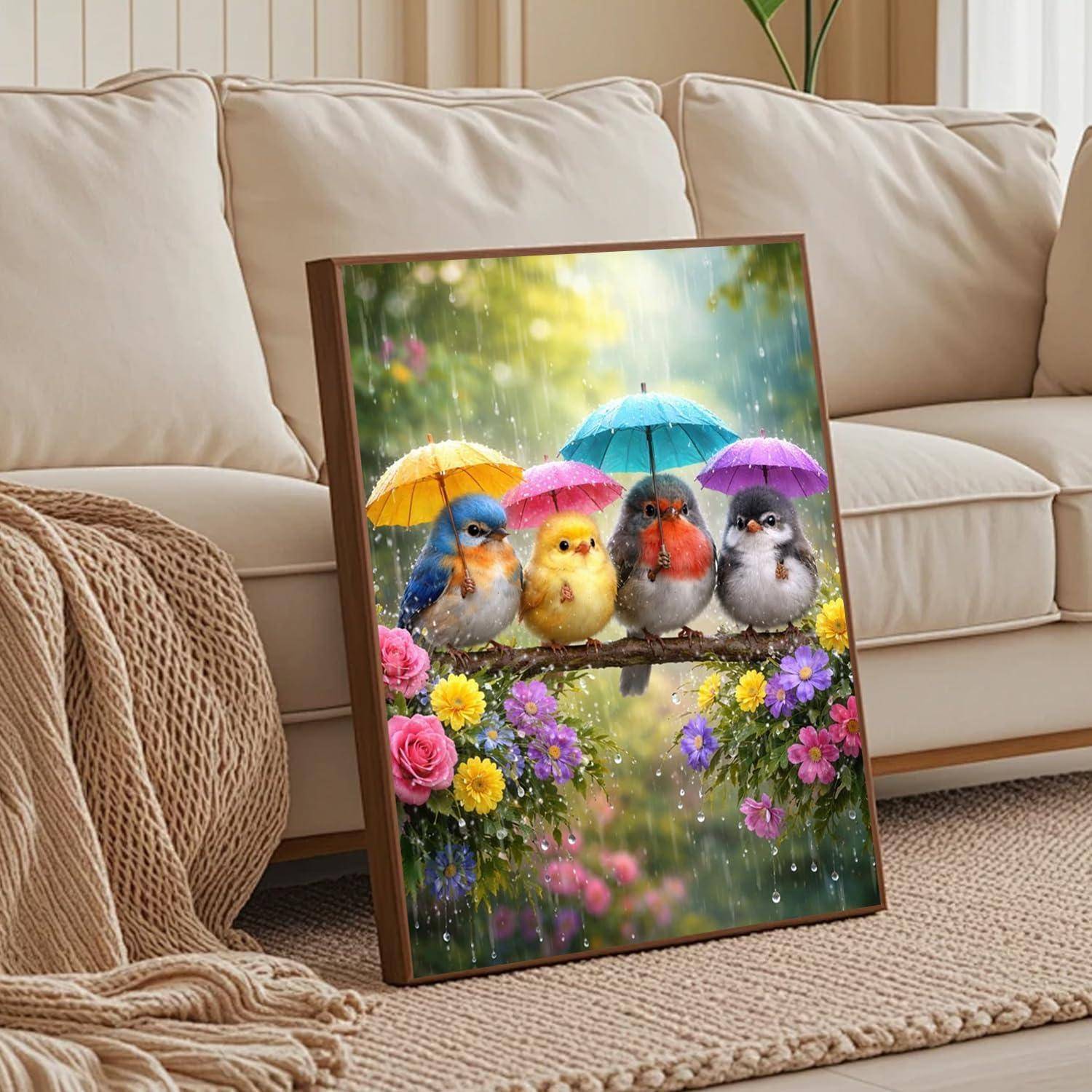 Gerahmtes Kunstwerk mit vier bunten Vögeln, die auf einem Ast unter Regenschirmen sitzen, mit Blumen und regnerischem Gartenhintergrund, gelehnt an ein Sofa.