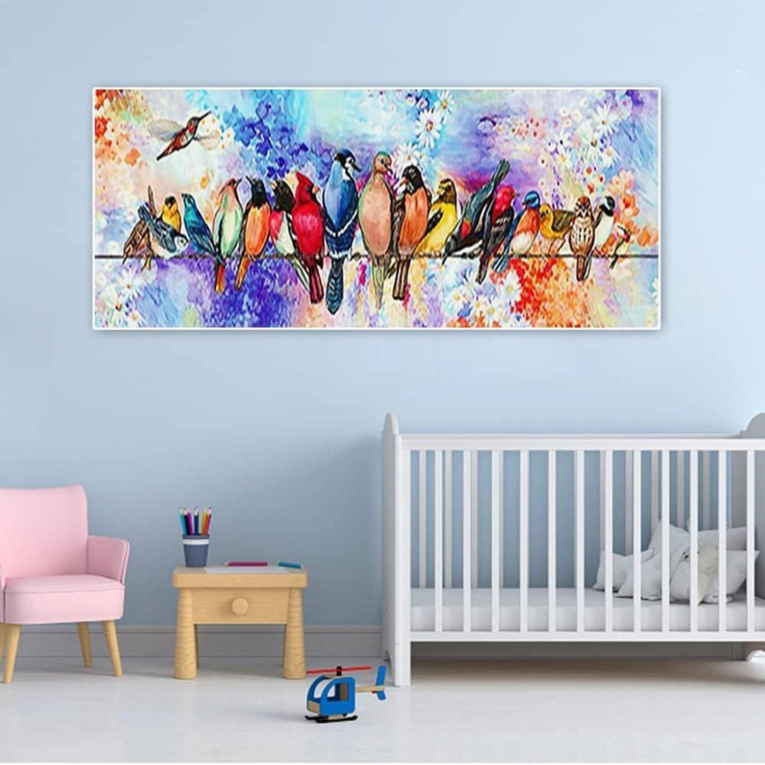 Buntes Gemälde von Vögeln, die auf einem Ast sitzen, hängt über einem Babybett in einem Kinderzimmer mit einem rosa Stuhl und einem kleinen Tisch.