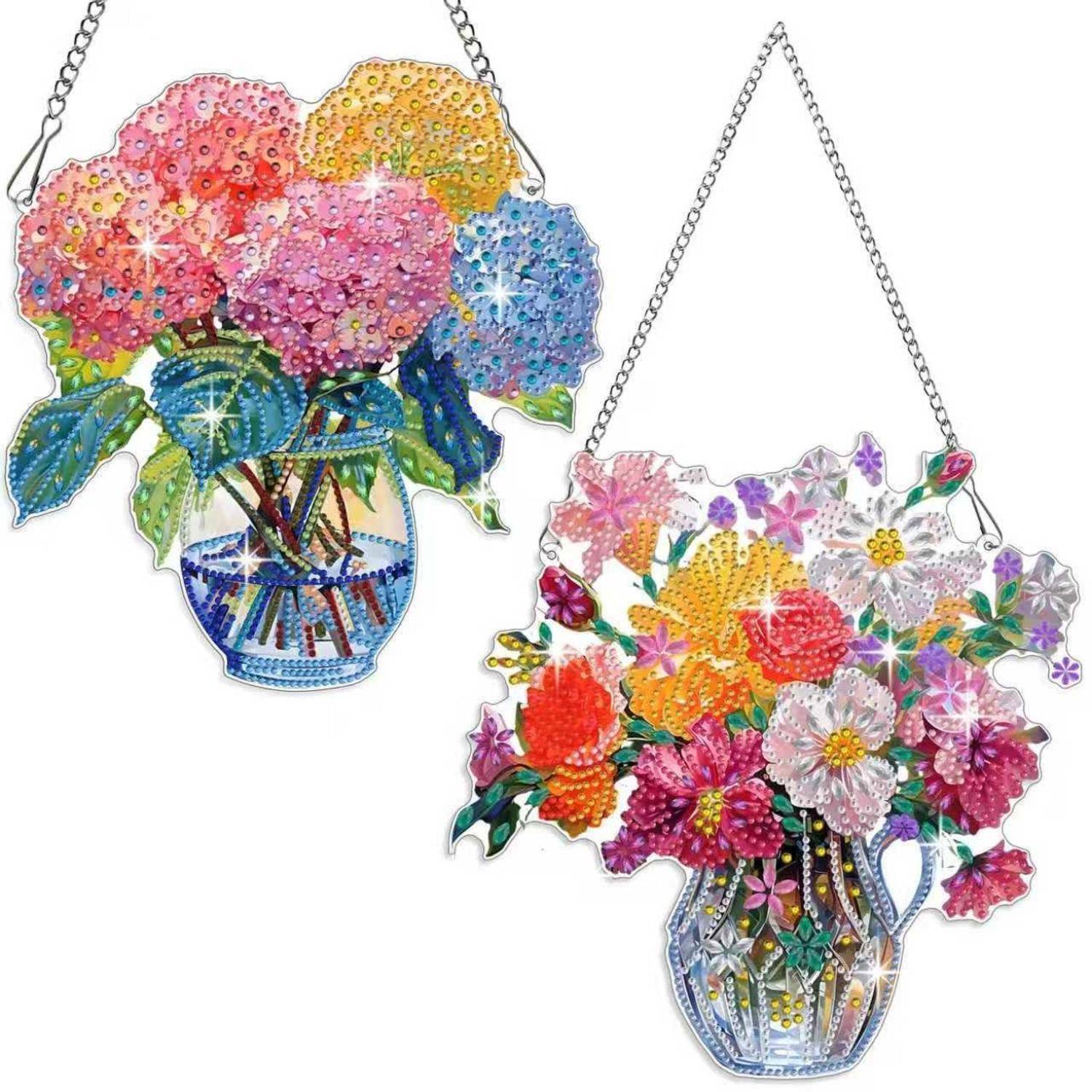 Zwei farbenfrohe florale Hängekeramiken mit geschmückten Straußdesigns in vasenförmigen Haltern an Ketten.