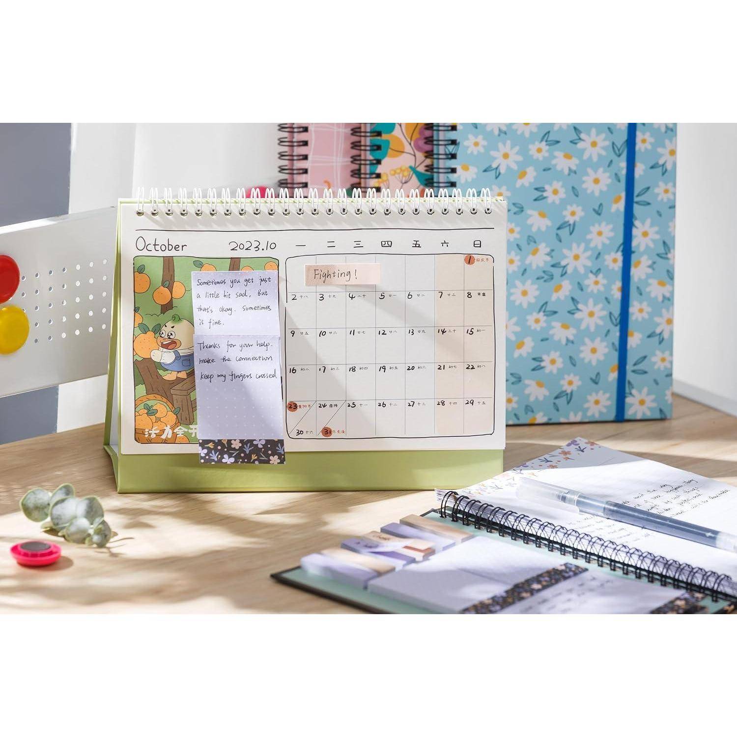 Desktopkalenderplaner offen bei Oktober 2023 auf einem Holztisch, mit Notizzetteln und Notizbüchern in der Nähe