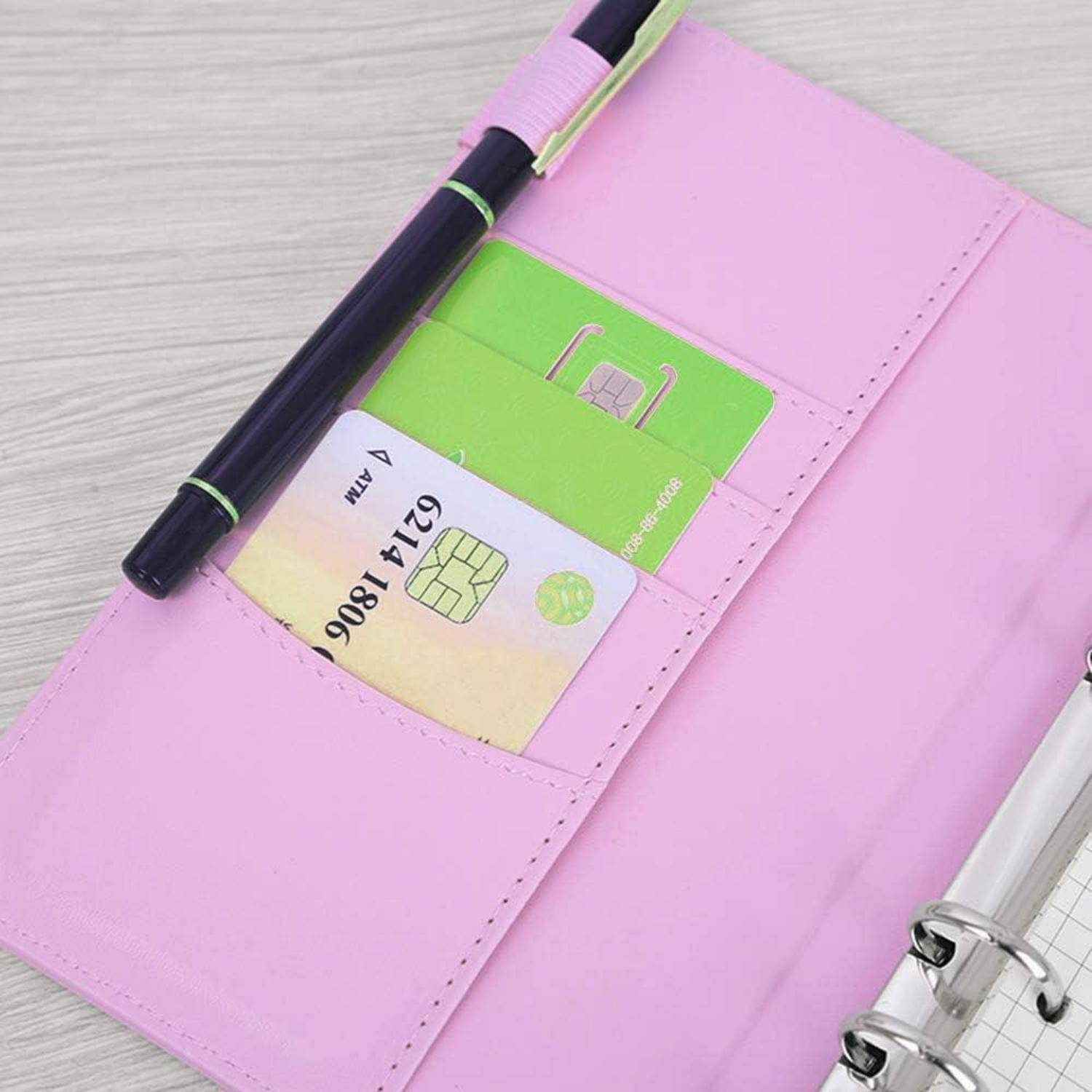 Rosa Ordner mit einer offenen Tasche, die einen schwarzen Stift, eine grüne Karte und eine Kreditkarte auf einem Schreibtisch enthält.