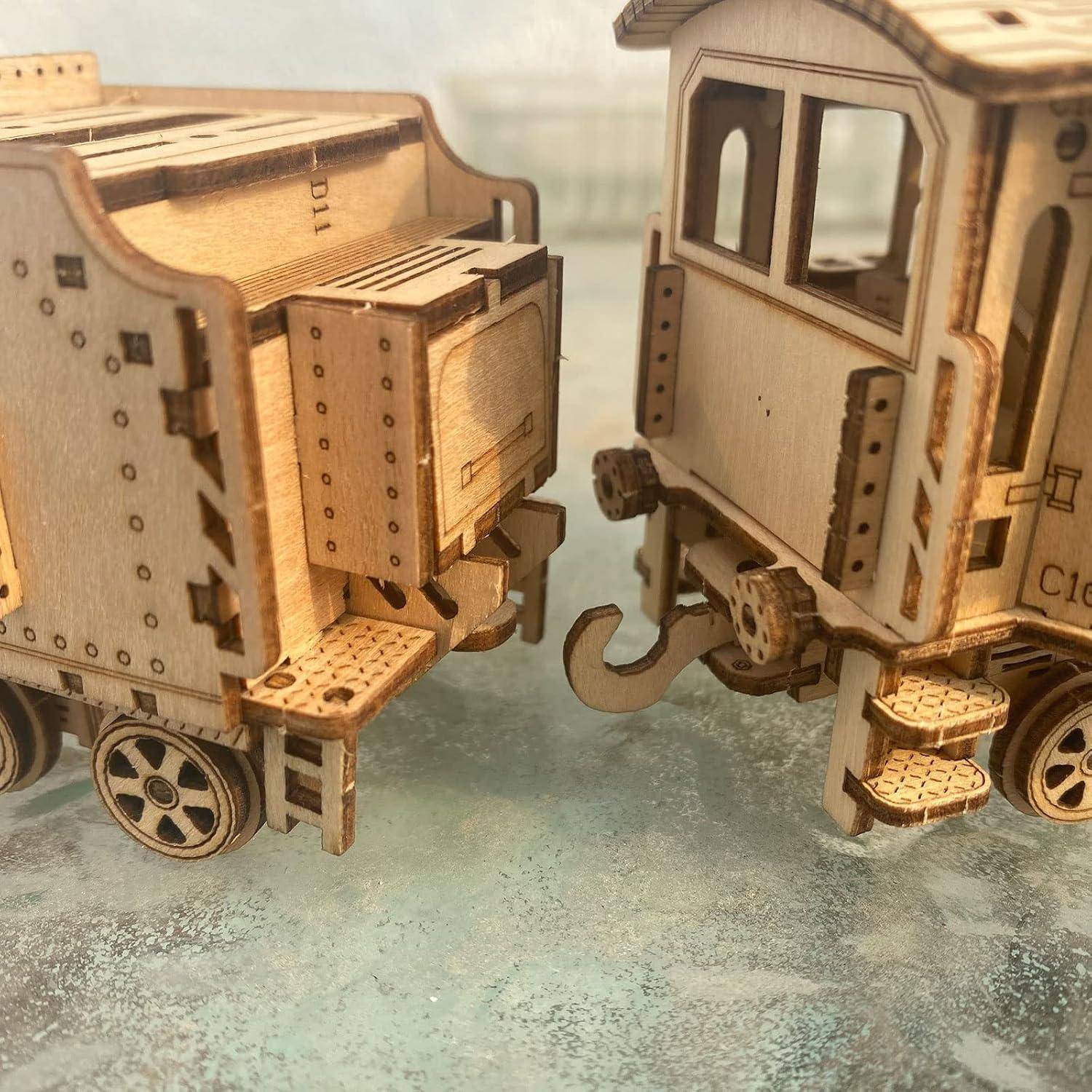 Zwei hölzerne Modelleisenbahn-Waggons sind zusammengekoppelt, aus der Nähe auf einer Tischplatte fotografiert.