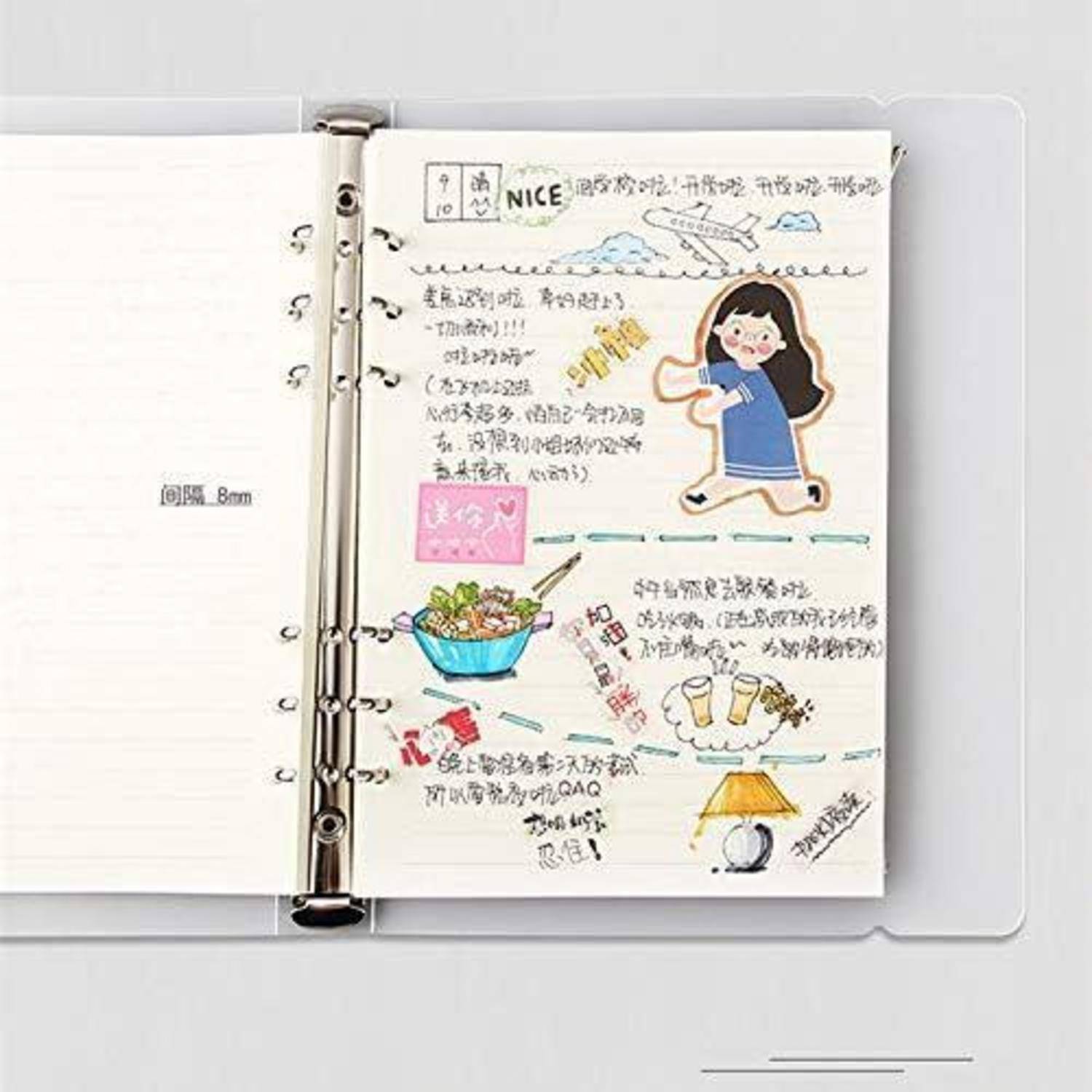 Ein offenes spiralgebundenes Notizbuch zeigt eine verzierte handgeschriebene Seite mit koreanischen Notizen, einem Cartoon-Mädchen, einem Flugzeug, einer Schüssel mit Essen und kleinen Kritzeleien.