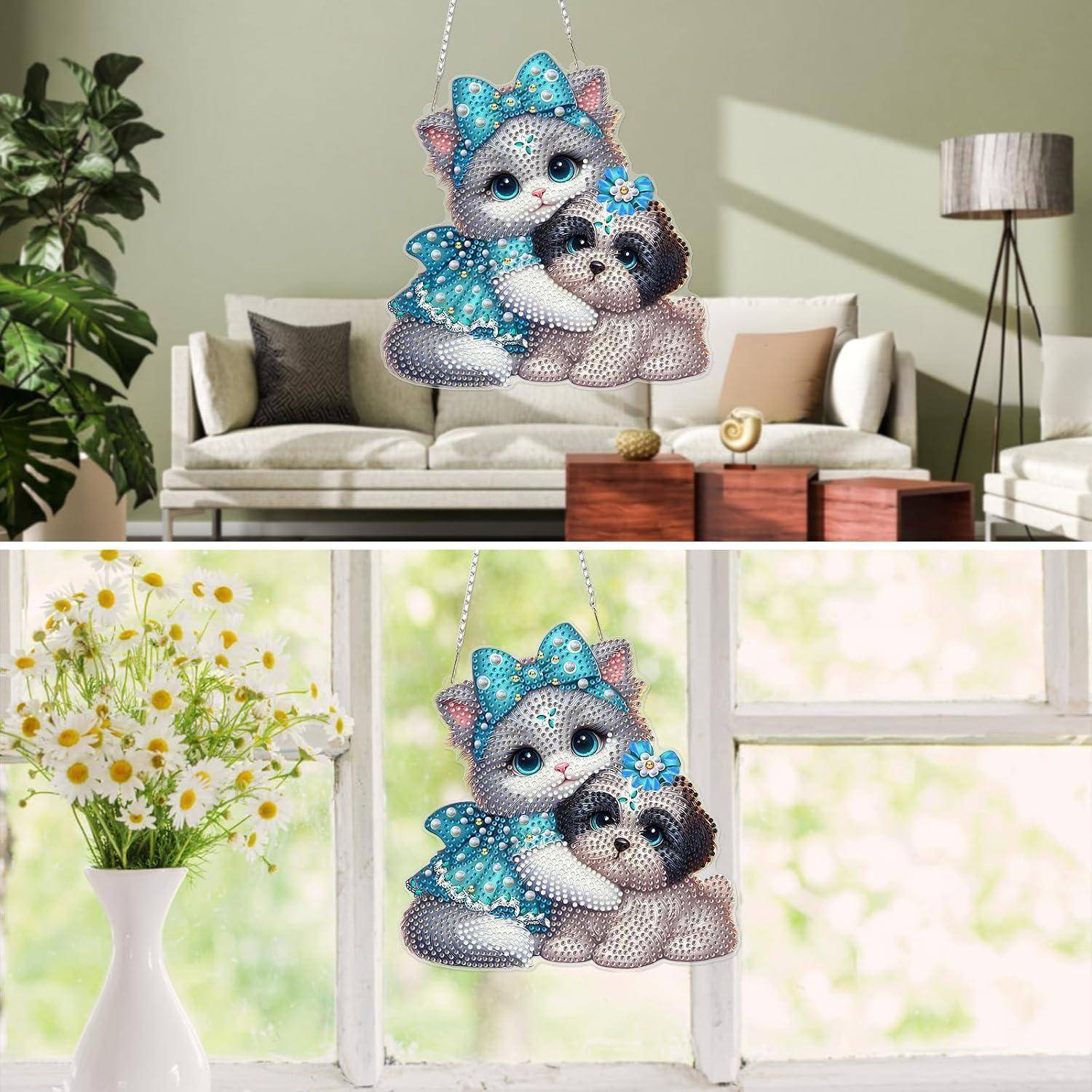 Dekoratives katzenförmiges Hängeornament mit zwei Cartoon-Kätzchen, gezeigt in einem Wohnzimmer und an einem Fenster neben Blumen.