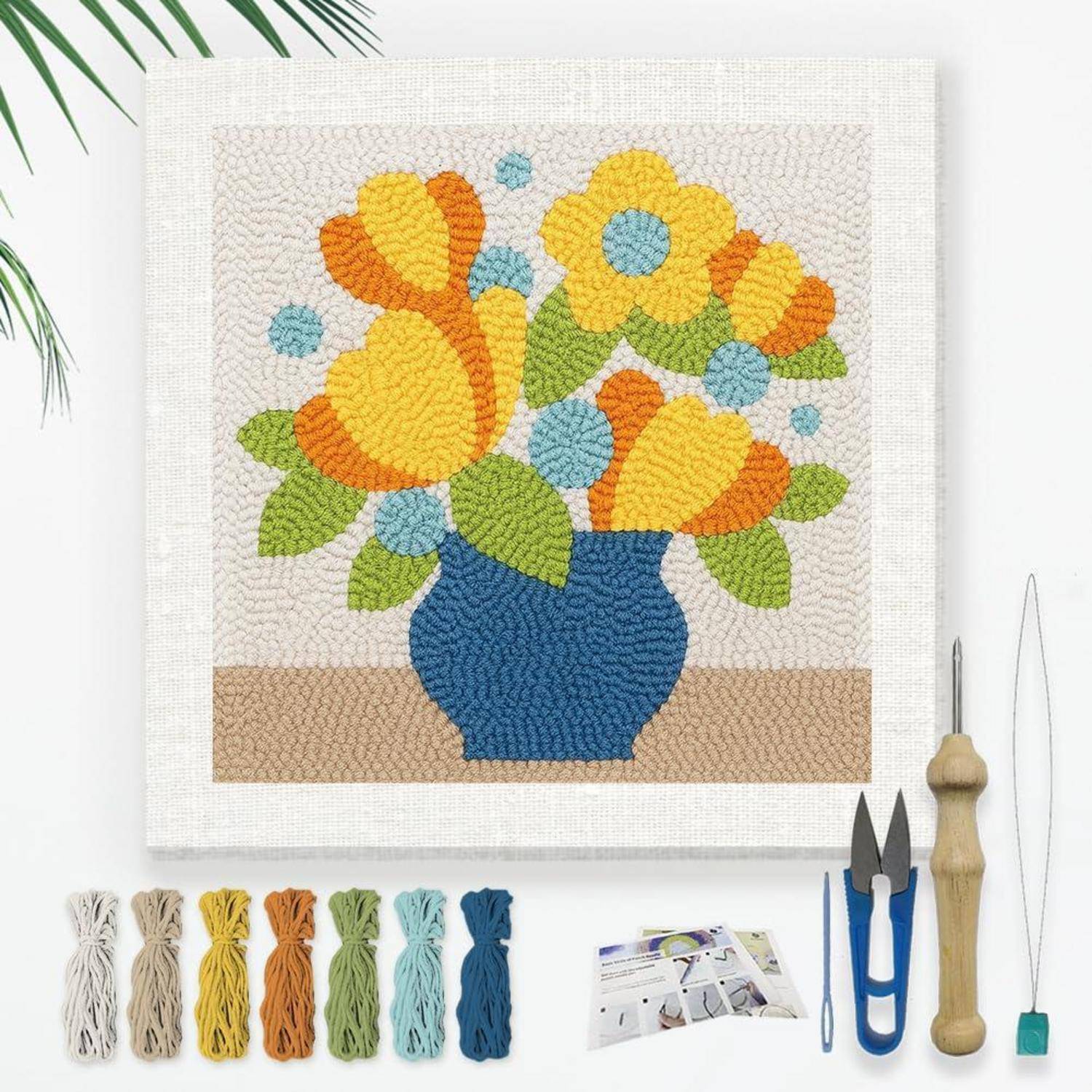 Bunte strukturierte Blumenwandkunst mit gelben, orangefarbenen und blauen Blumen in einer blauen Vase, gezeigt mit Garnbündeln und Nadelarbeitsgeräten für ein Bastelset.