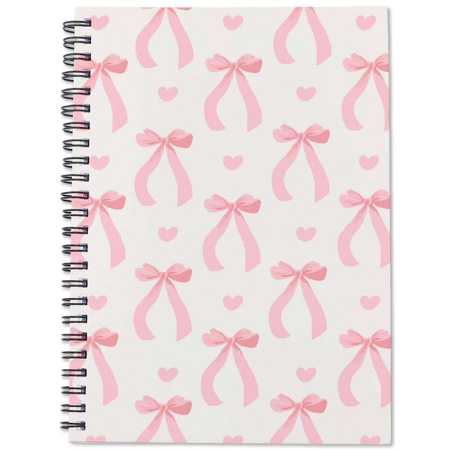 Weißes Spiralbindung-Notizbuch mit rosa Schleife und Herzmuster auf dem Umschlag.