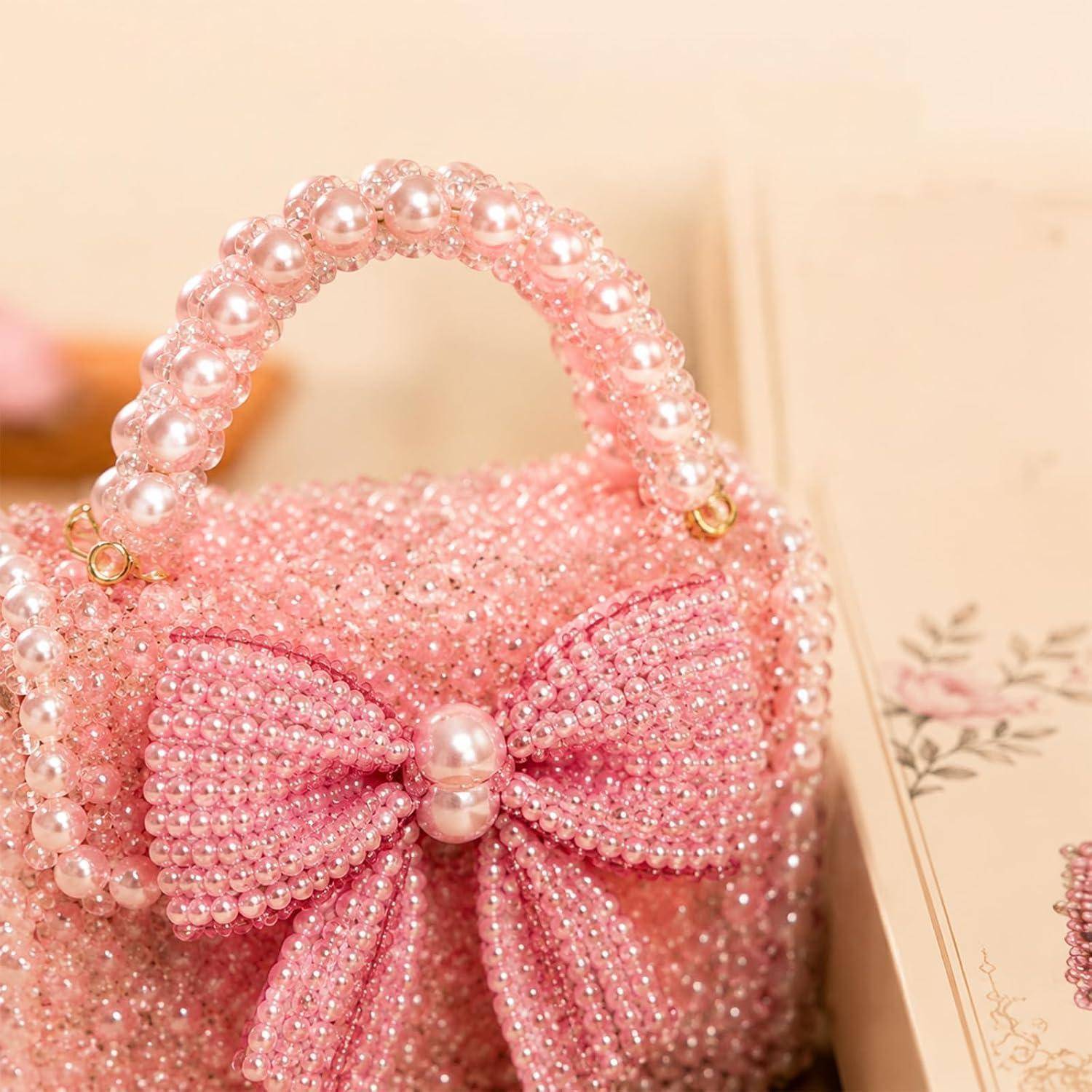 Rosa Perlenhandtasche mit Perlmutt-Griff und großer Schleife, präsentiert auf einer dekorativen Oberfläche.