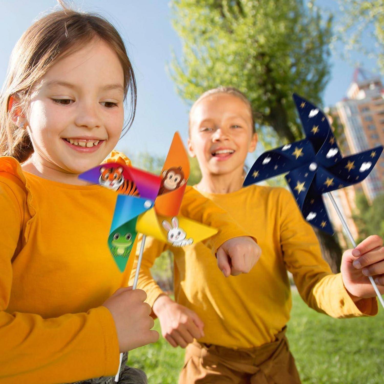 Zwei lächelnde Kinder in gelben Hemden im Freien, die bunte Windräder an einem sonnigen Tag halten.