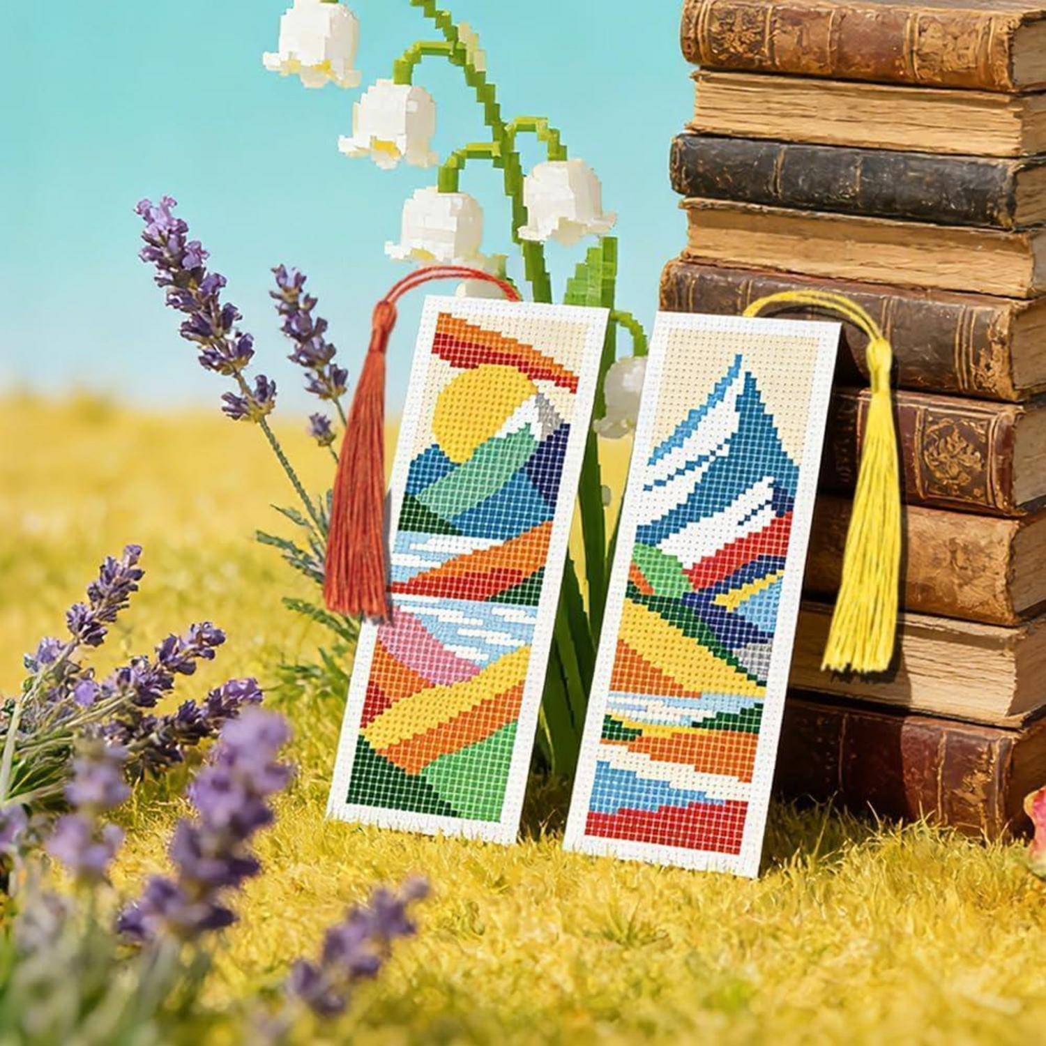 Zwei farbenfrohe Kreuzstich-Lesezeichen mit Quasten, die an einem Stapel alter Bücher lehnen, umgeben von Lavendel- und Maiglöckchen-Blüten.