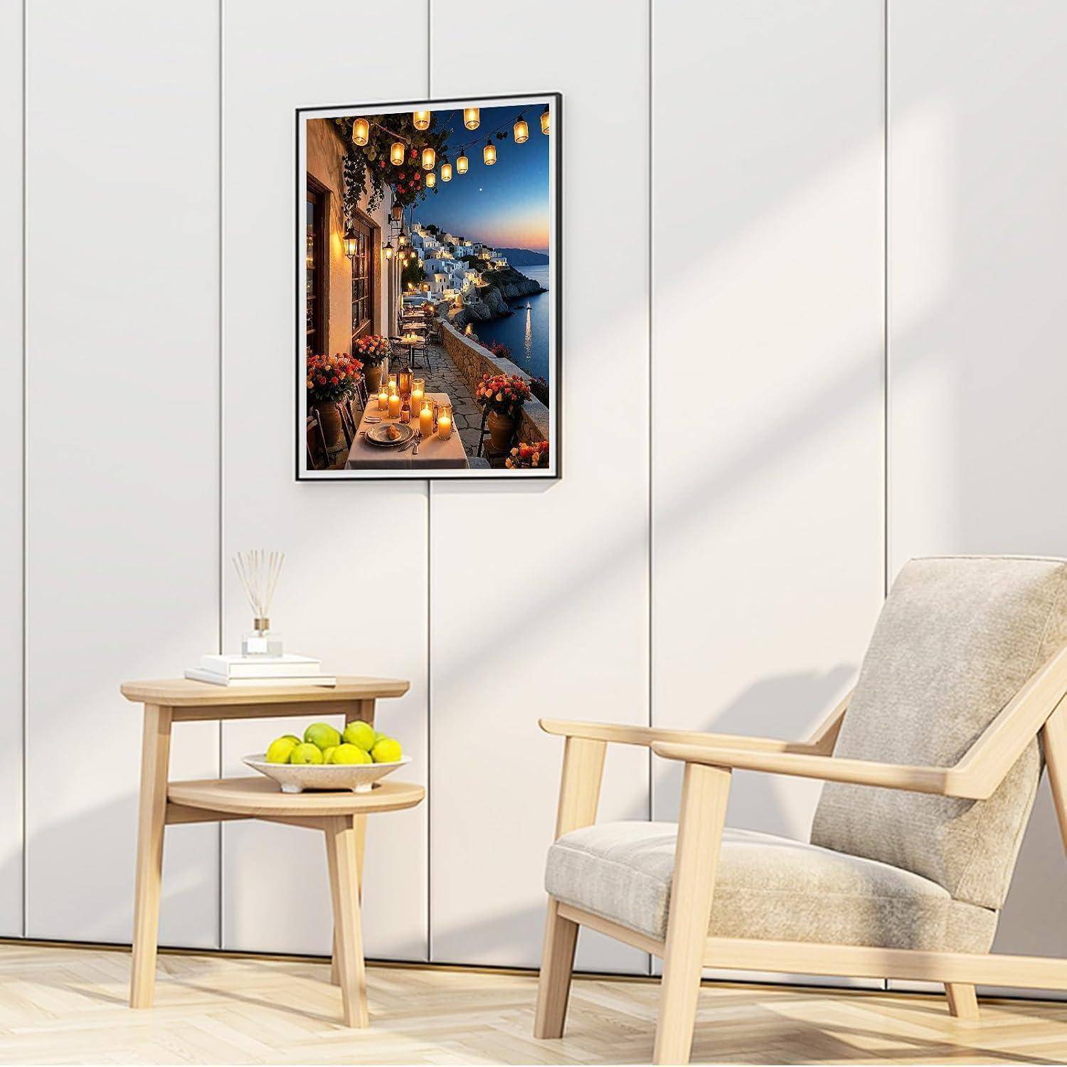 Minimalistisches Zimmer mit einem gerahmten Küstensonnenunergangsdruckan der Wand, einem beigefarbenen Sessel und einem kleinen Beistelltisch mit Büchern, Diffusor und einer Schüssel grüner Äpfel.
