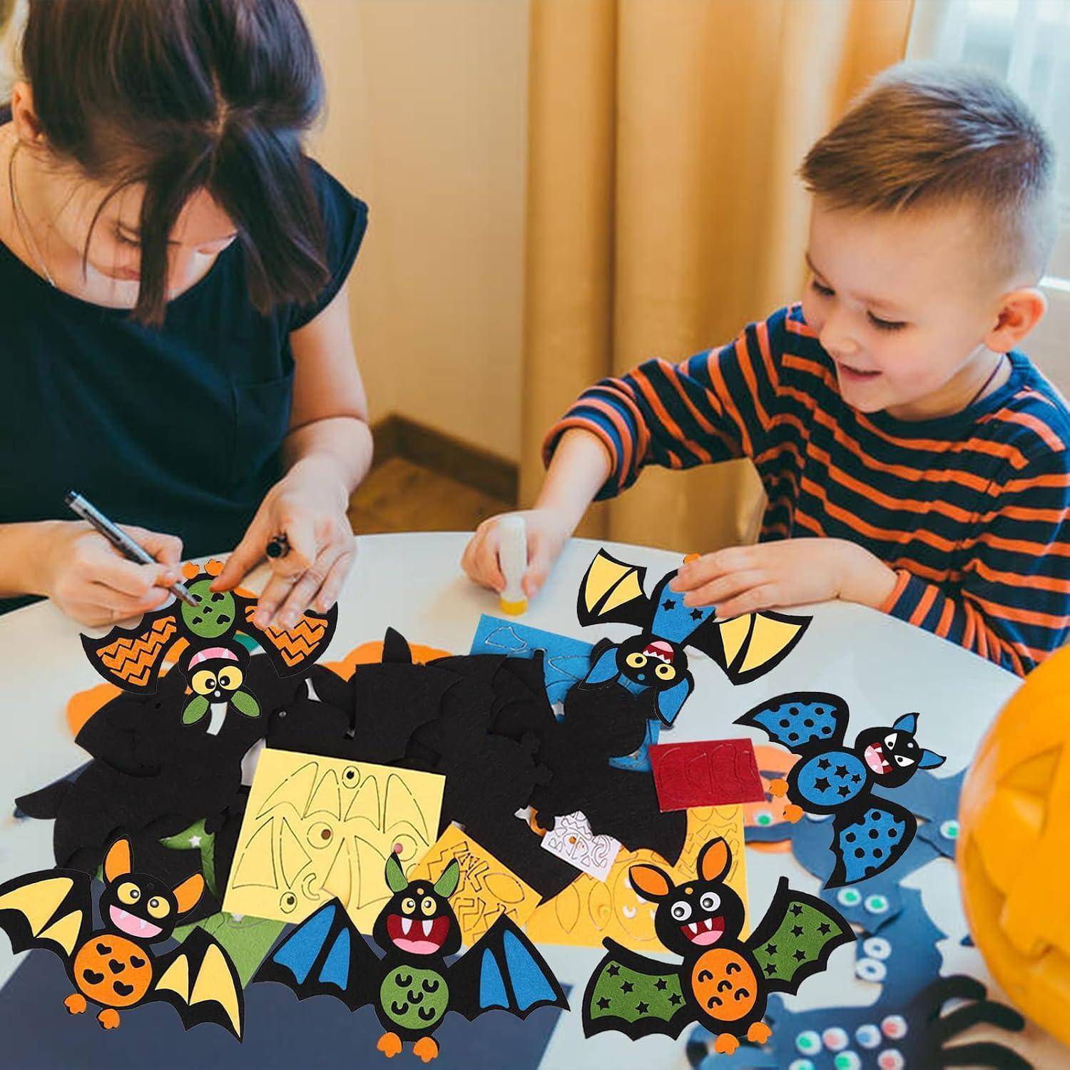 Ein Erwachsener und ein kleiner Junge basteln an einem Tisch mit Halloween-Fledermäusen. Der Tisch ist mit bunten ausgeschnittenen Fledermäusen und Papierdekoration bedeckt.