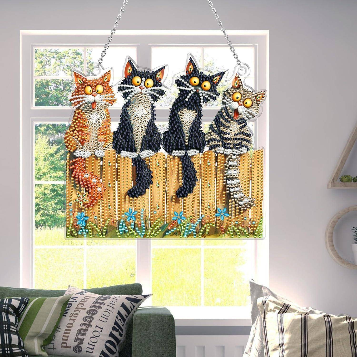 Perlenbesetzte Hängdekoration mit vier Katzen, die auf einem Zaun vor einem Fenster sitzen